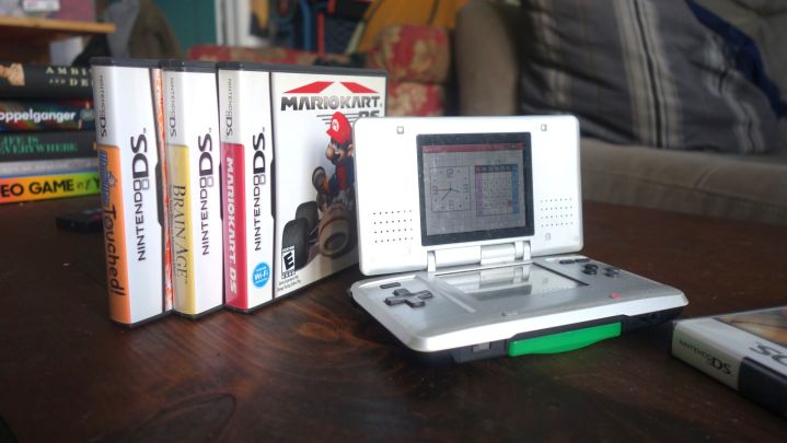 Une Nintendo DS est posée sur une table avec quelques boîtes de jeux.