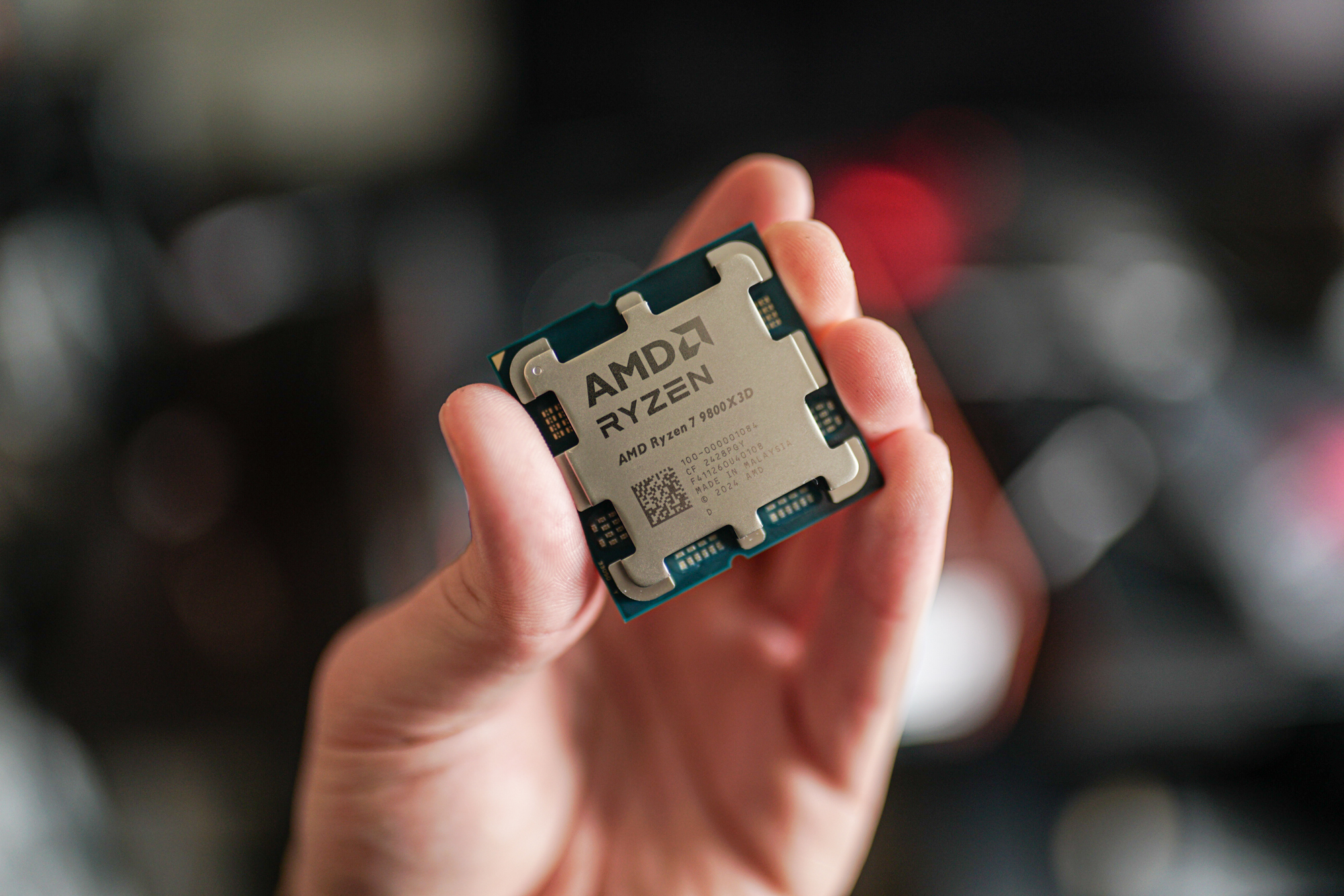 Le Ryzen 7 9800X3D tenu entre des doigts.
