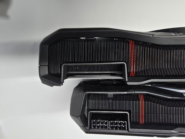 Gros plan sur une carte graphique d'ordinateur avec des ailettes de refroidissement et des accents rouges sur fonds blanc.