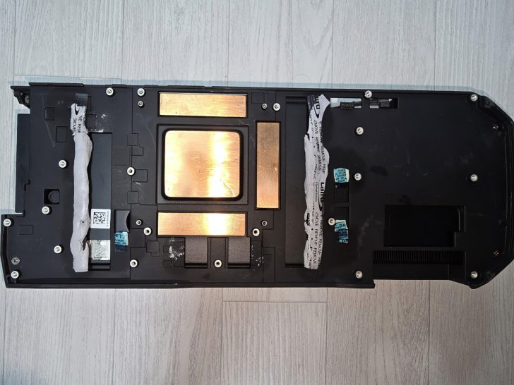 Plaque de refroidissement GPU d'ordinateur avec des pads thermiques sur une surface en bois clair.