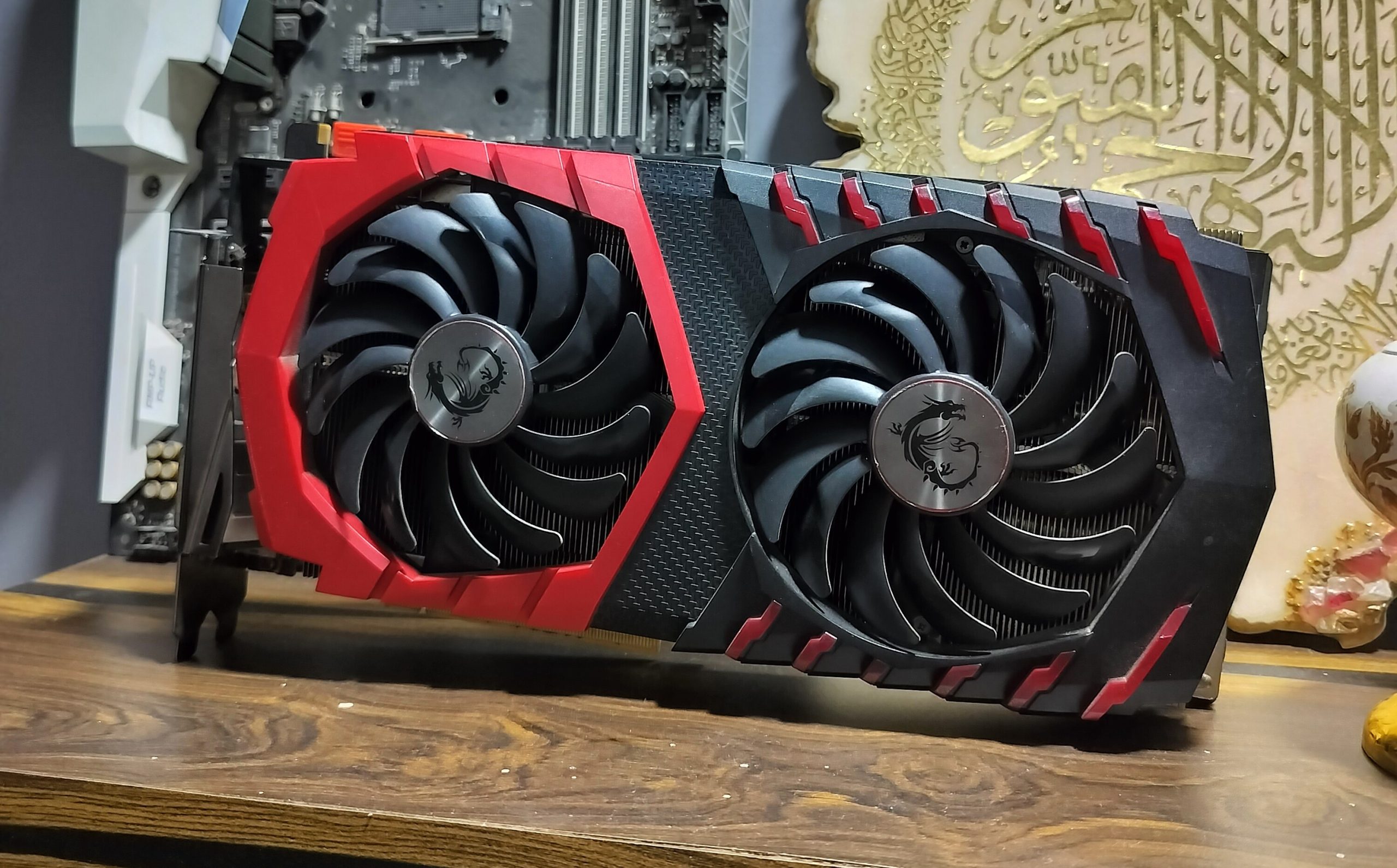 Carte graphique de jeu rouge et noire avec double ventilateur sur une surface en bois.