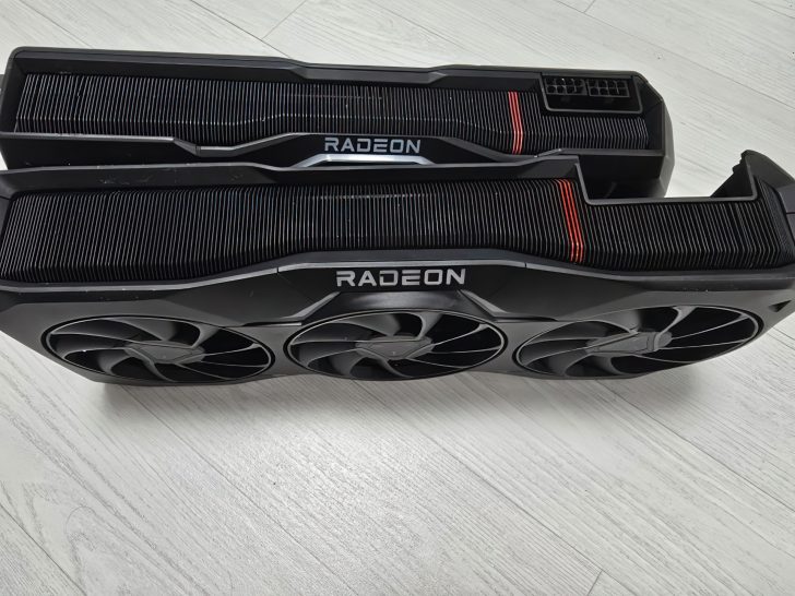 Deux cartes graphiques Radeon sur une surface blanche, montrant un design de refroidissement à trois ventilateurs.