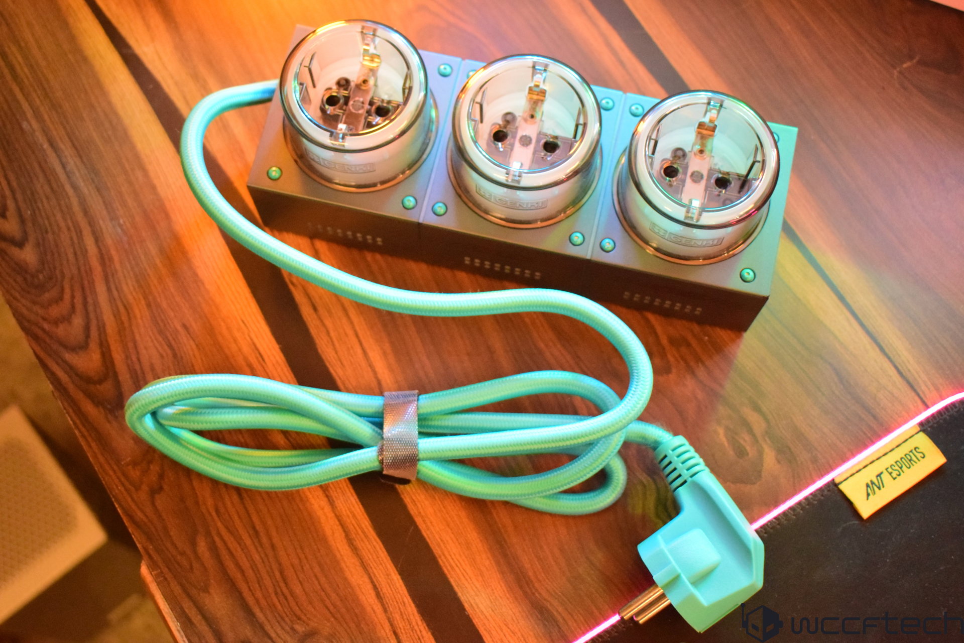 Triple power socket and turquoise cord on wooden desk.