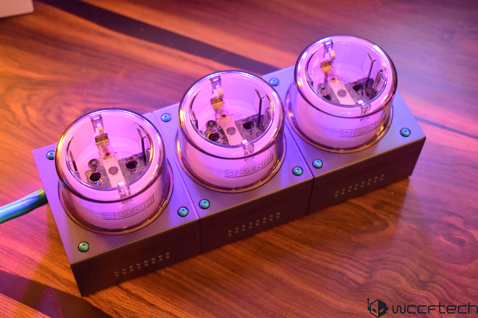 Purple-lit power socket unit on wooden table.