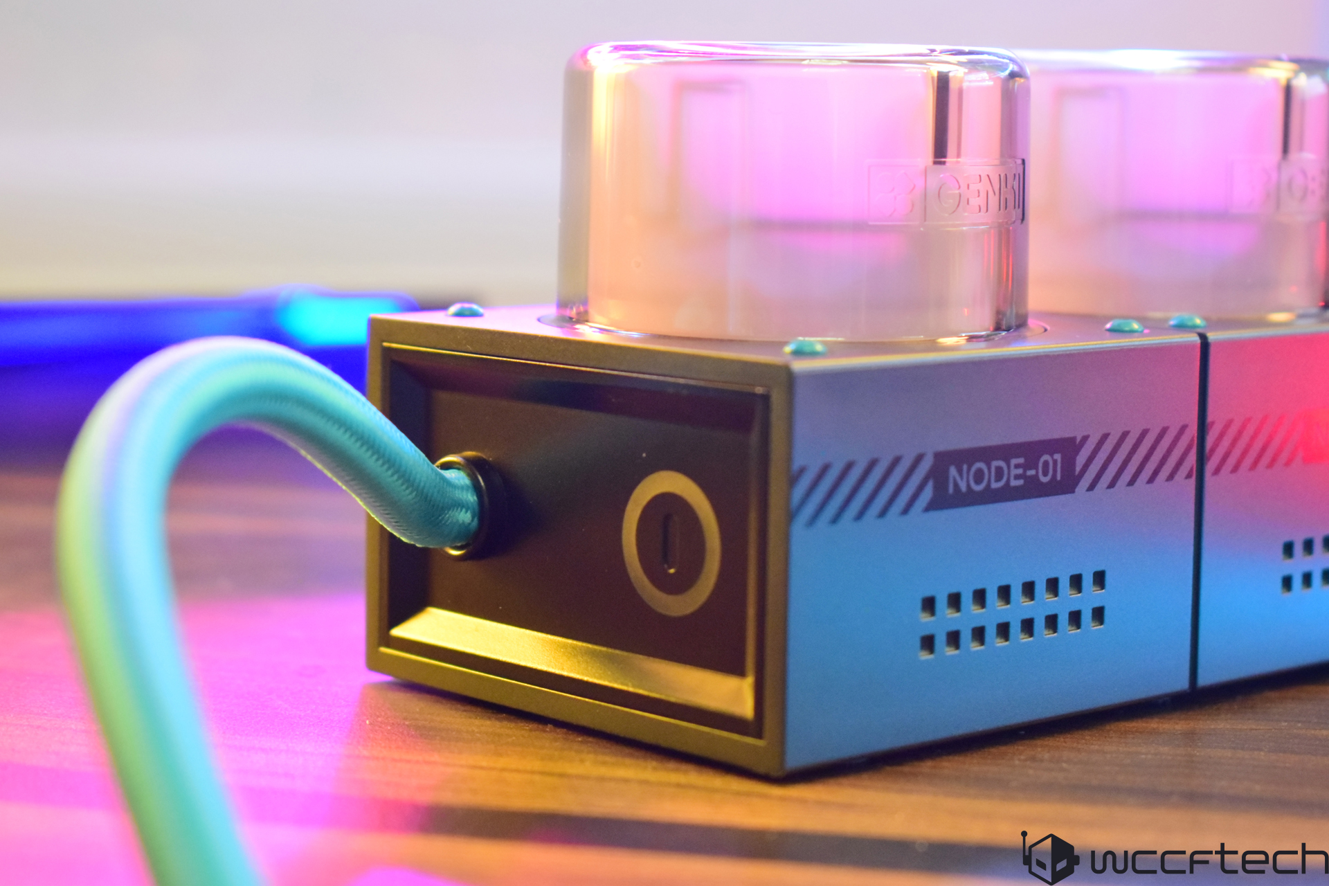 Tech gadget with blue cable and labeled NODE-01, bathed in colorful ambient lighting.