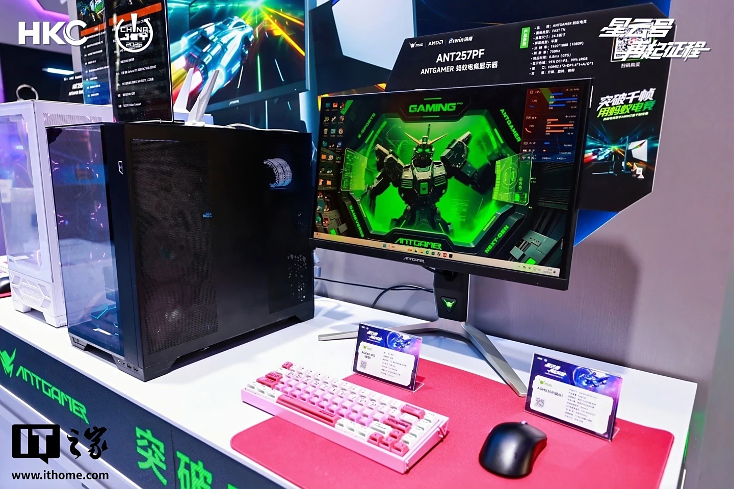 Configuration de jeu avec le moniteur AntGamer, PC noir, clavier rose et souris sur un tapis rouge.