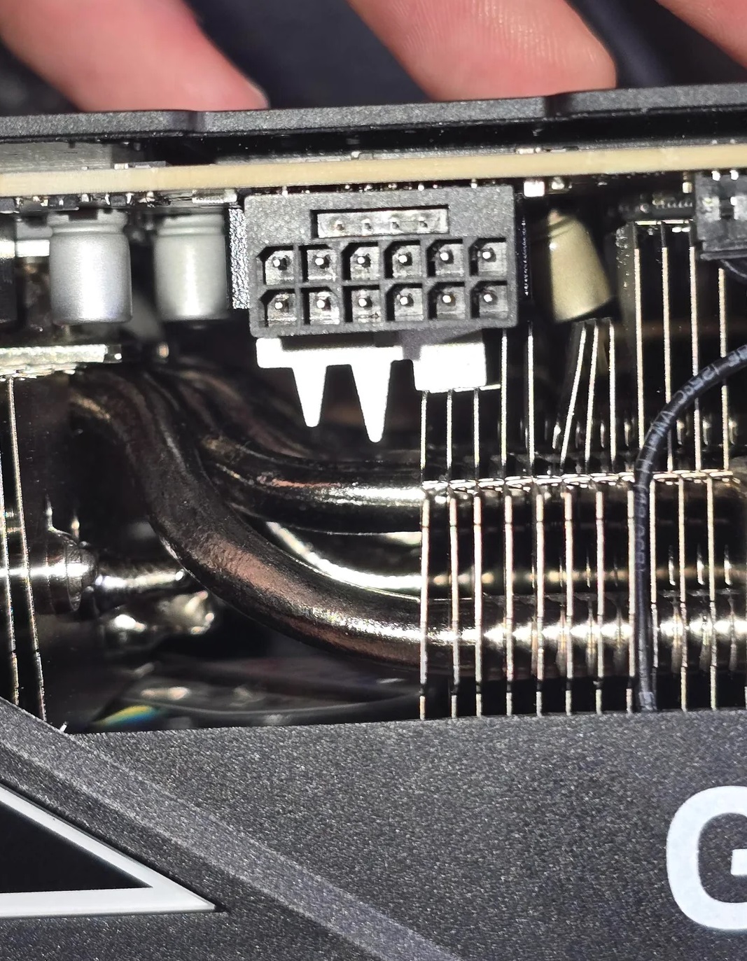 Détail d'une carte graphique montrant des ailettes de refroidissement et la prise d'alimentation.