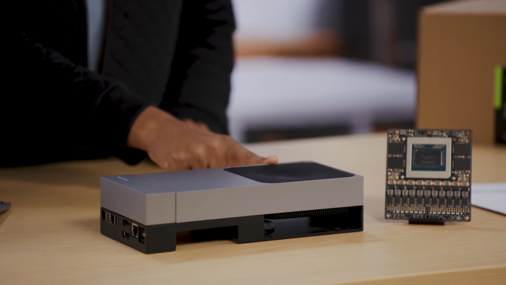 A person demonstrating a compact computer on a table next to a detached circuit board.