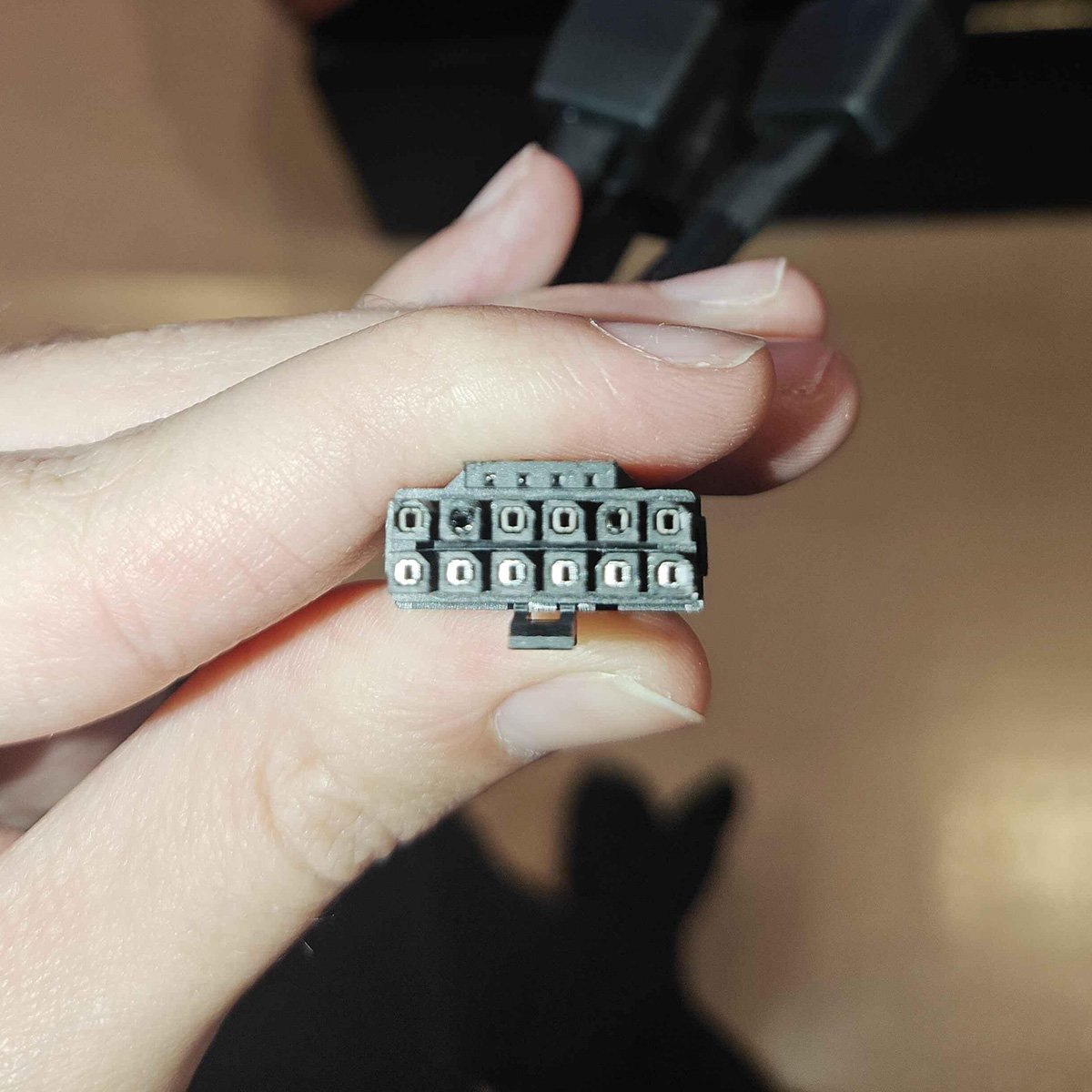 Connecteur 12V-2x6, illuminé par une lampe de poche, montrant une décoloration sur plusieurs broches.