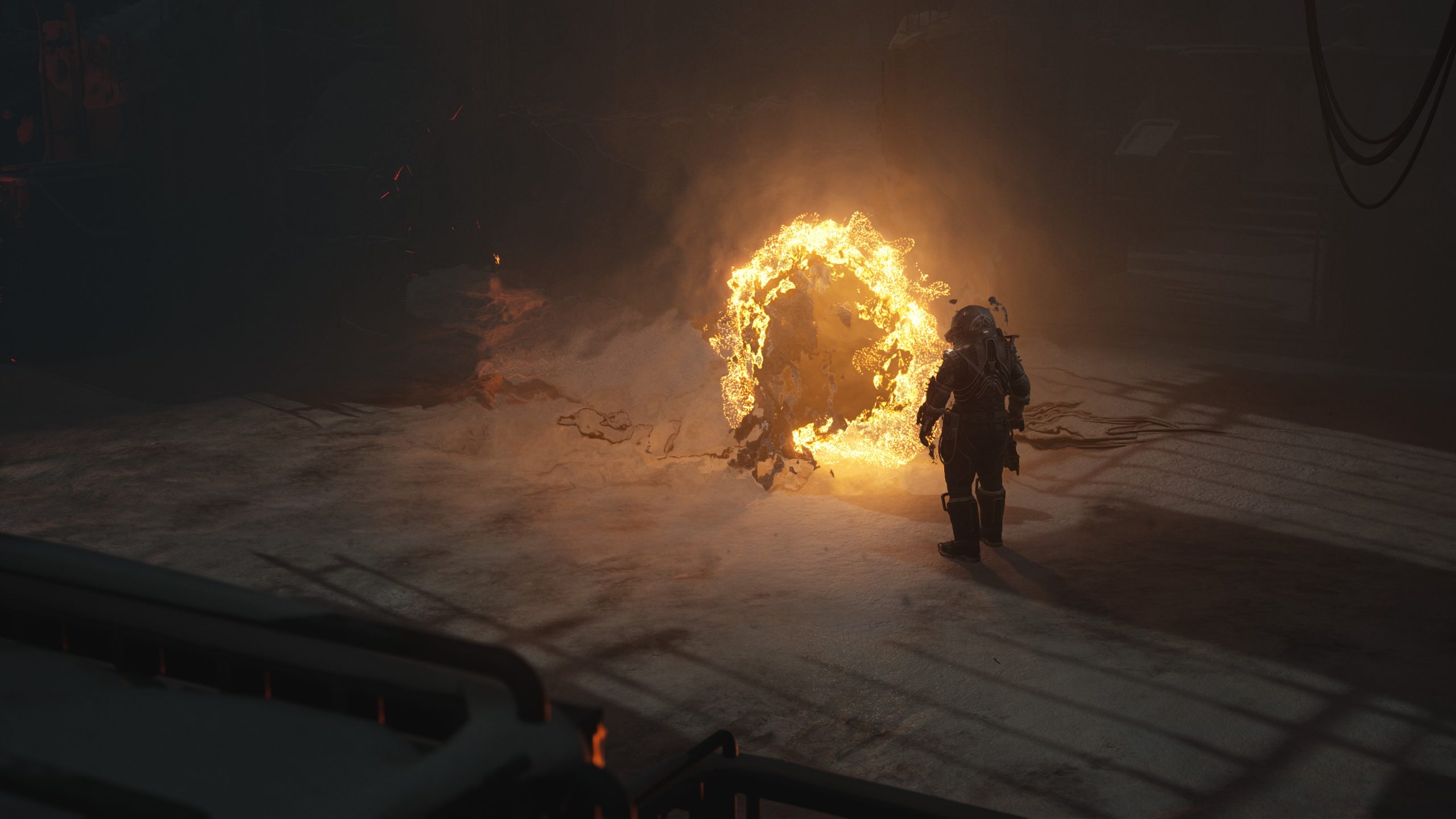 Une figure en costume sombre fait face à un portail de flammes dans un espace industriel faiblement éclairé.