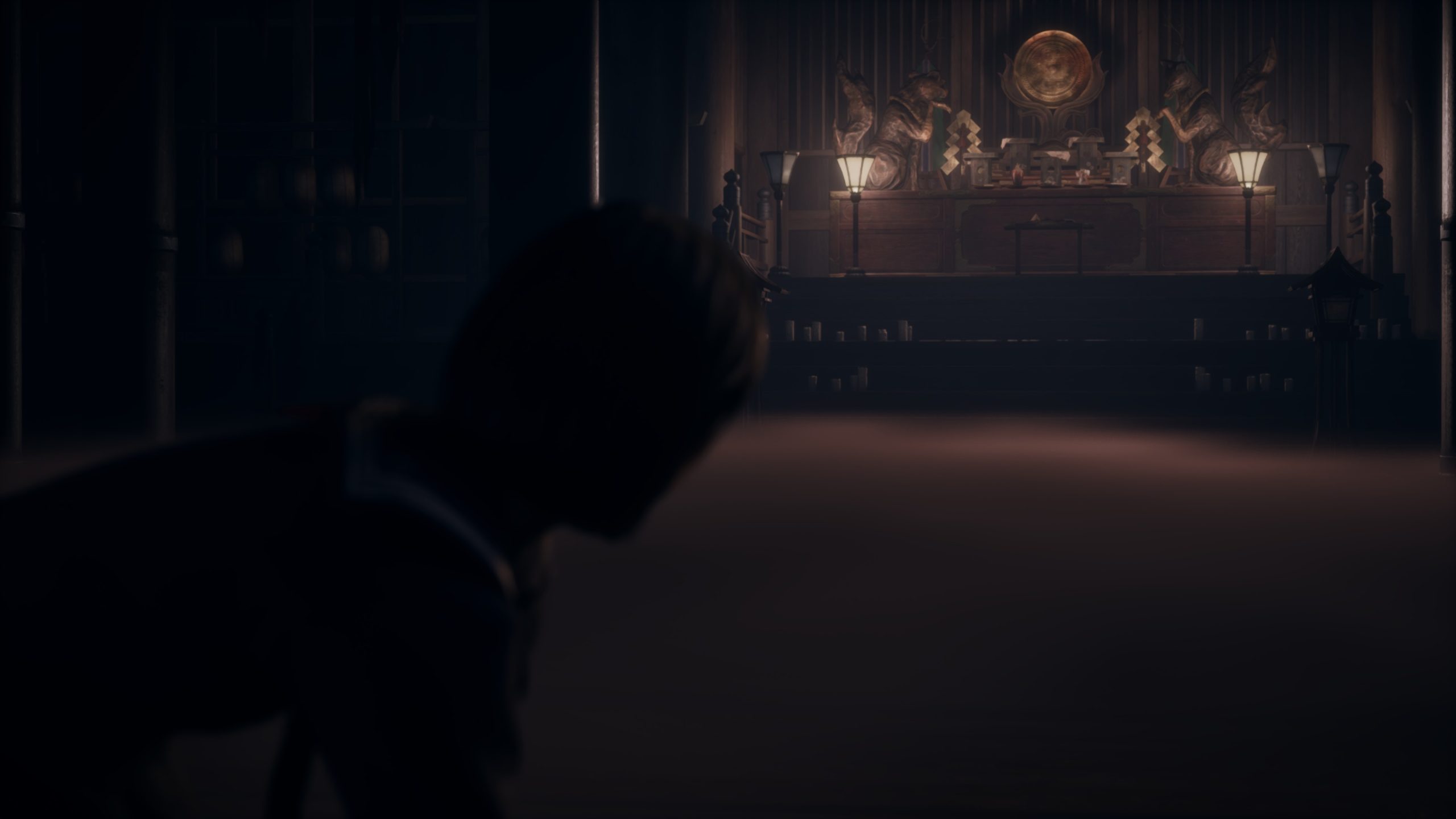 Chambre sombre avec des figures sur un autel, éclairage tamisé.