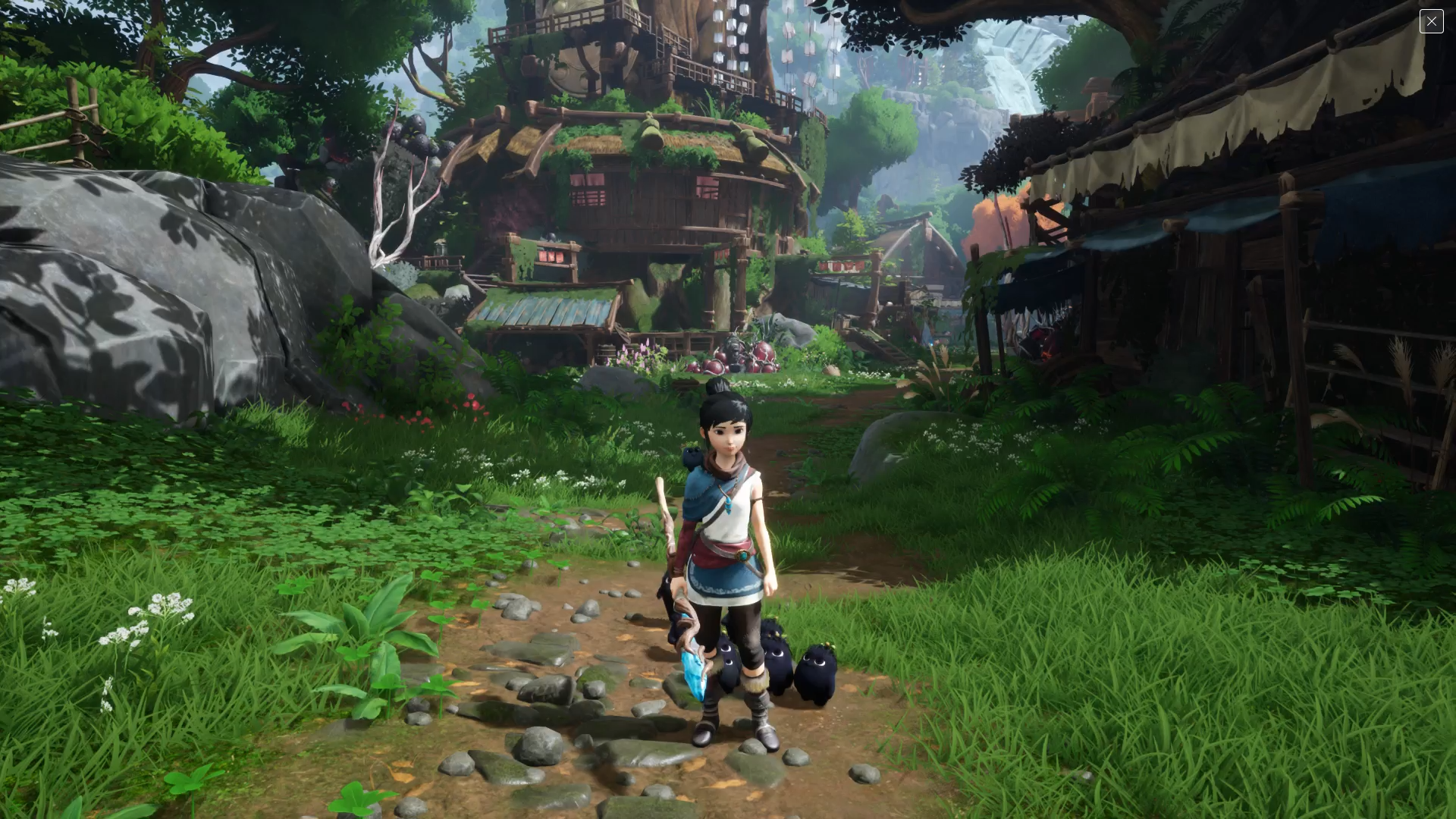 Personnage dans un environnement de Kena: Bridge of Spirits avec un bâton.