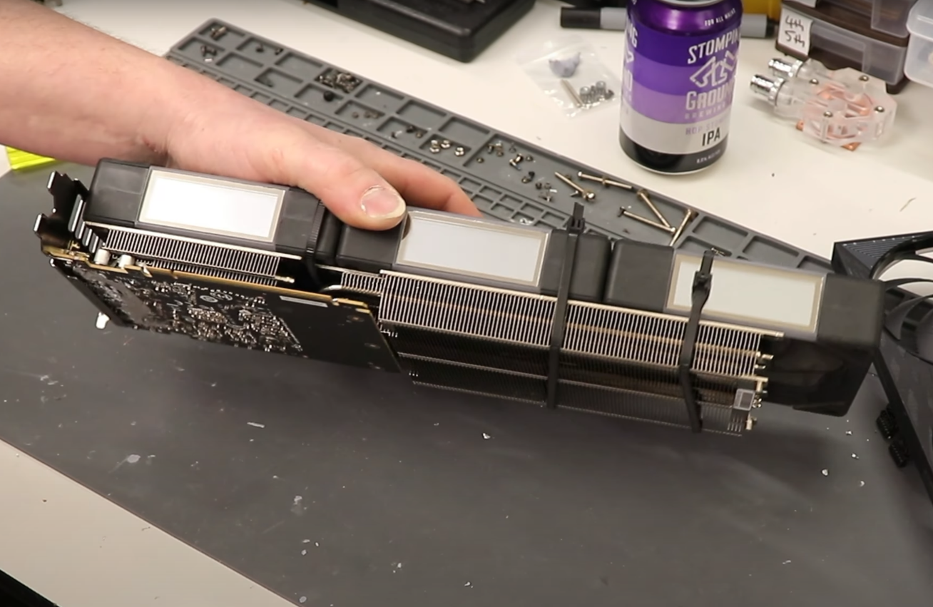 Main tenant un refroidisseur GPU non marqué sur un bureau encombré.