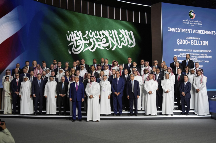 Groupe de personnes sur scène devant un écran affichant le forum d'investissement Saudi-U.S. 2023 et des accords d'investissement dépassant les 300 milliards de dollars.
