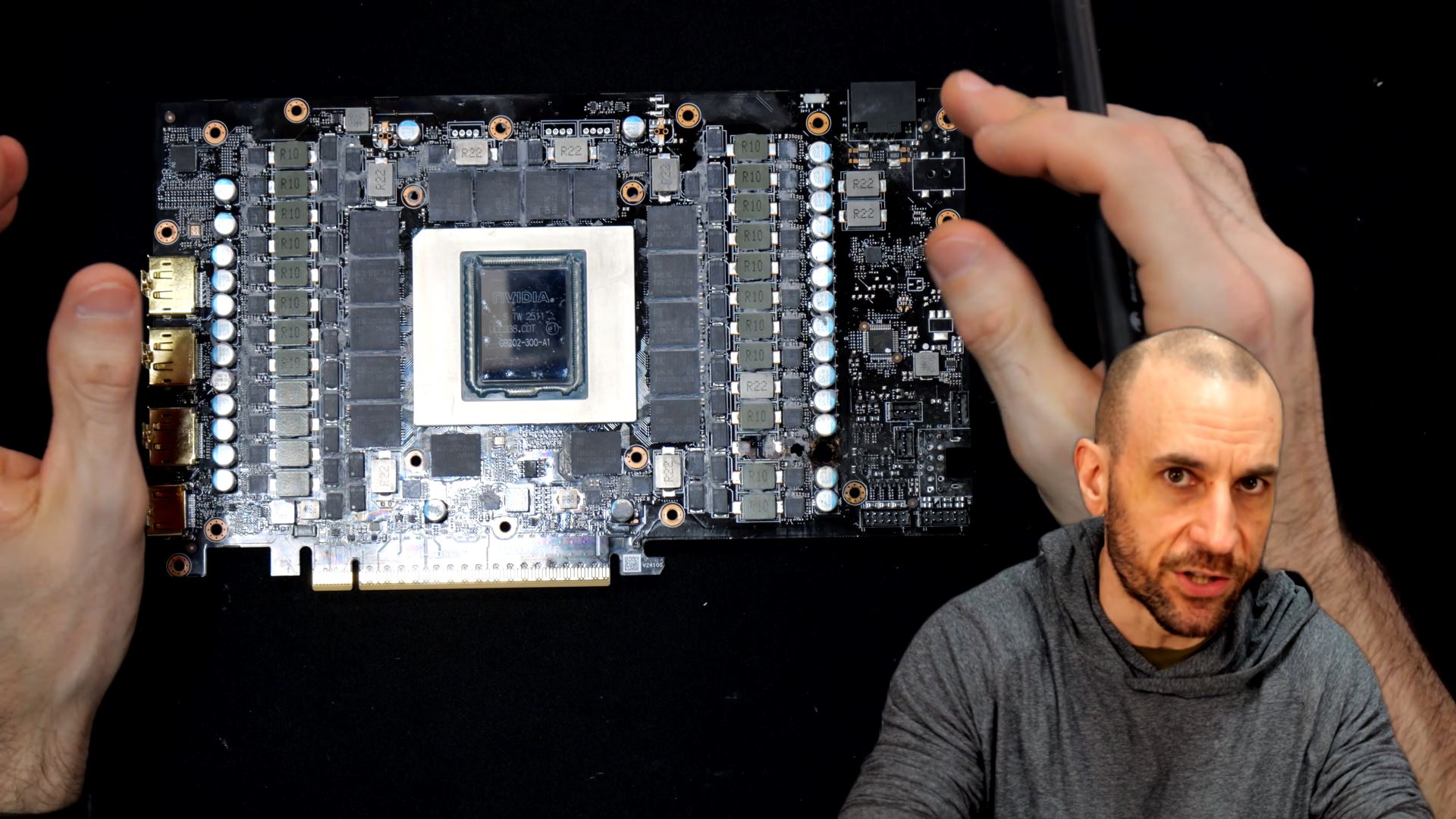 Une personne examine une carte graphique NVIDIA à nu montrant son circuit et sa puce, avec une autre personne en arrière-plan.