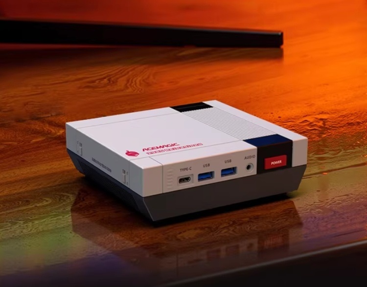 A mini PC in a retro gaming console design labeled ACEMAGIC, featuring Type-C, USB, and audio ports, rests on a wooden
