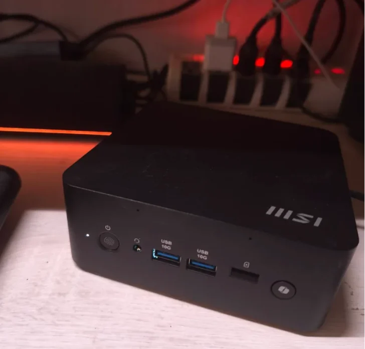 Un mini PC MSI sur un bureau avec des ports visibles étiquetés 'USB 10G' et un bouton d'alimentation éclairé.