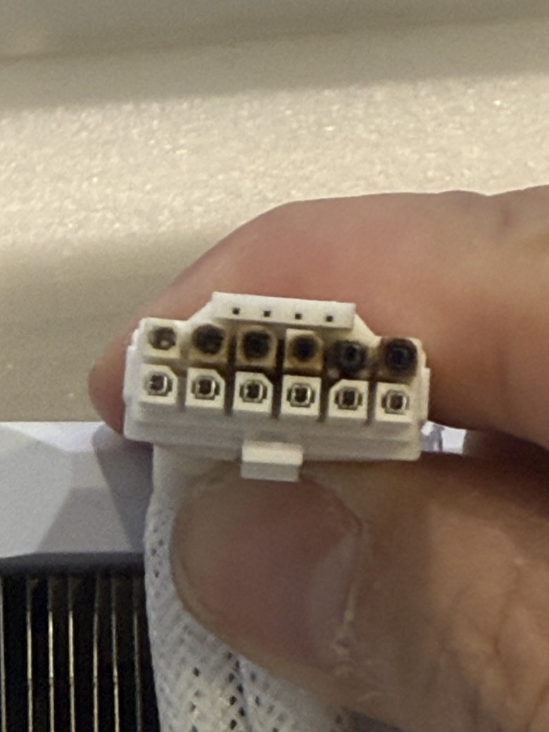 Gros plan d'un connecteur d'alimentation partiellement brûlé.