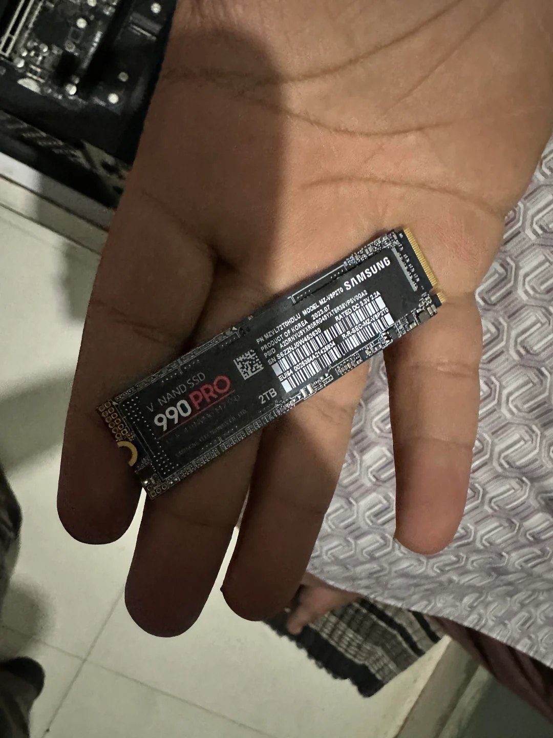 Un Samsung 990 Pro NVMe SSD étiqueté '2 To' dans la main d'une personne.