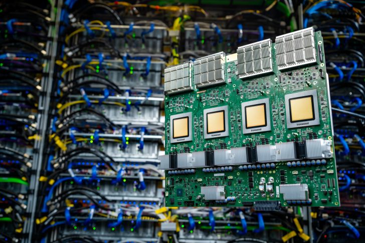 Un circuit imprimé vert étiqueté 'Ironwood', avec quatre grandes puces et dissipateurs de chaleur, devant des racks de serveurs.