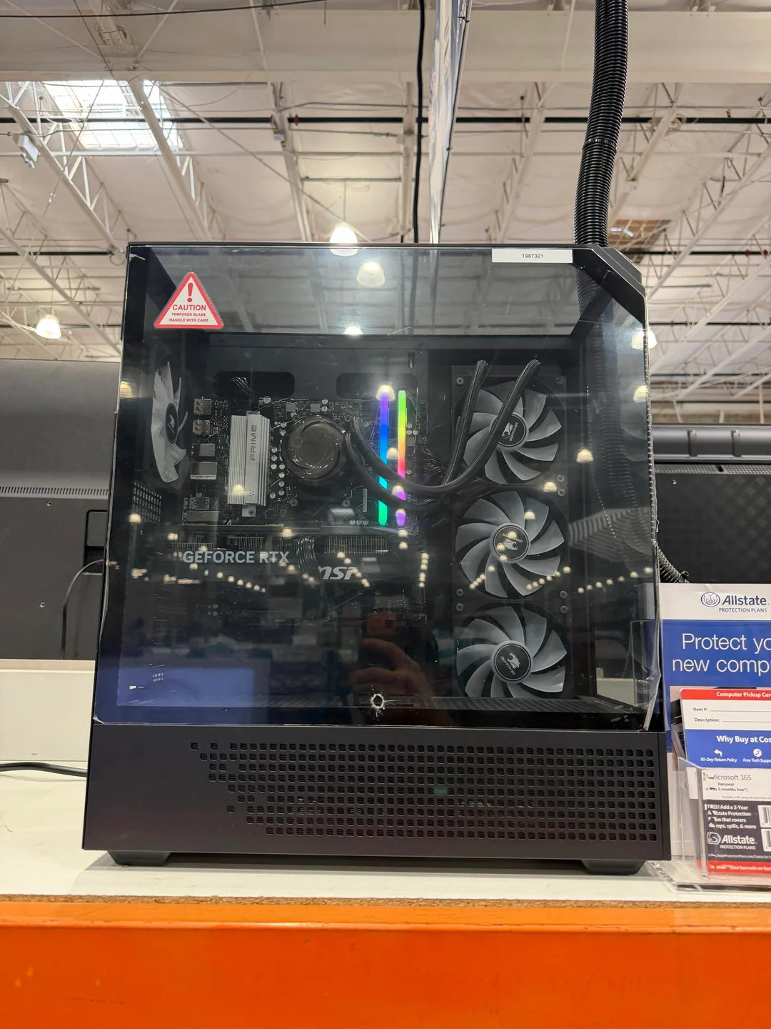 Un PC de bureau avec le logo 'GeForce RTX' visible à l'intérieur, équipé d'éclairage RGB et de ventilateurs de refroidissement, exposé dans un magasin.