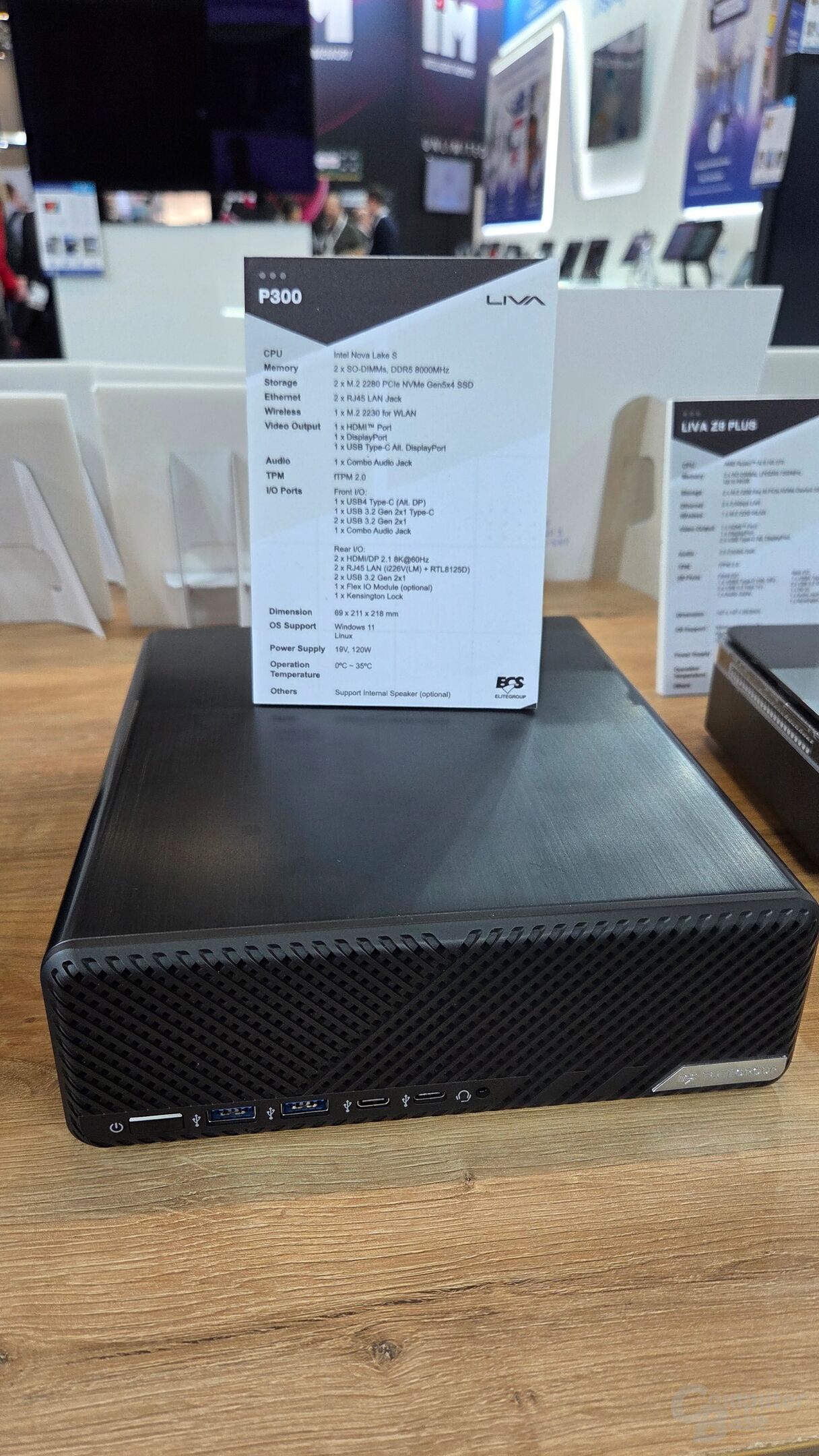 Un mini PC LIVA P300 exposé sur une surface en bois avec une fiche technique affichant des caractéristiques comme CPU Intel Nova Lake S, mémoire DDR5 8000MT/s, SSD PCIe NVMe Gen5x4, sorties HDMI et DisplayPort, ainsi que compatibilité Linux et Windows 11.