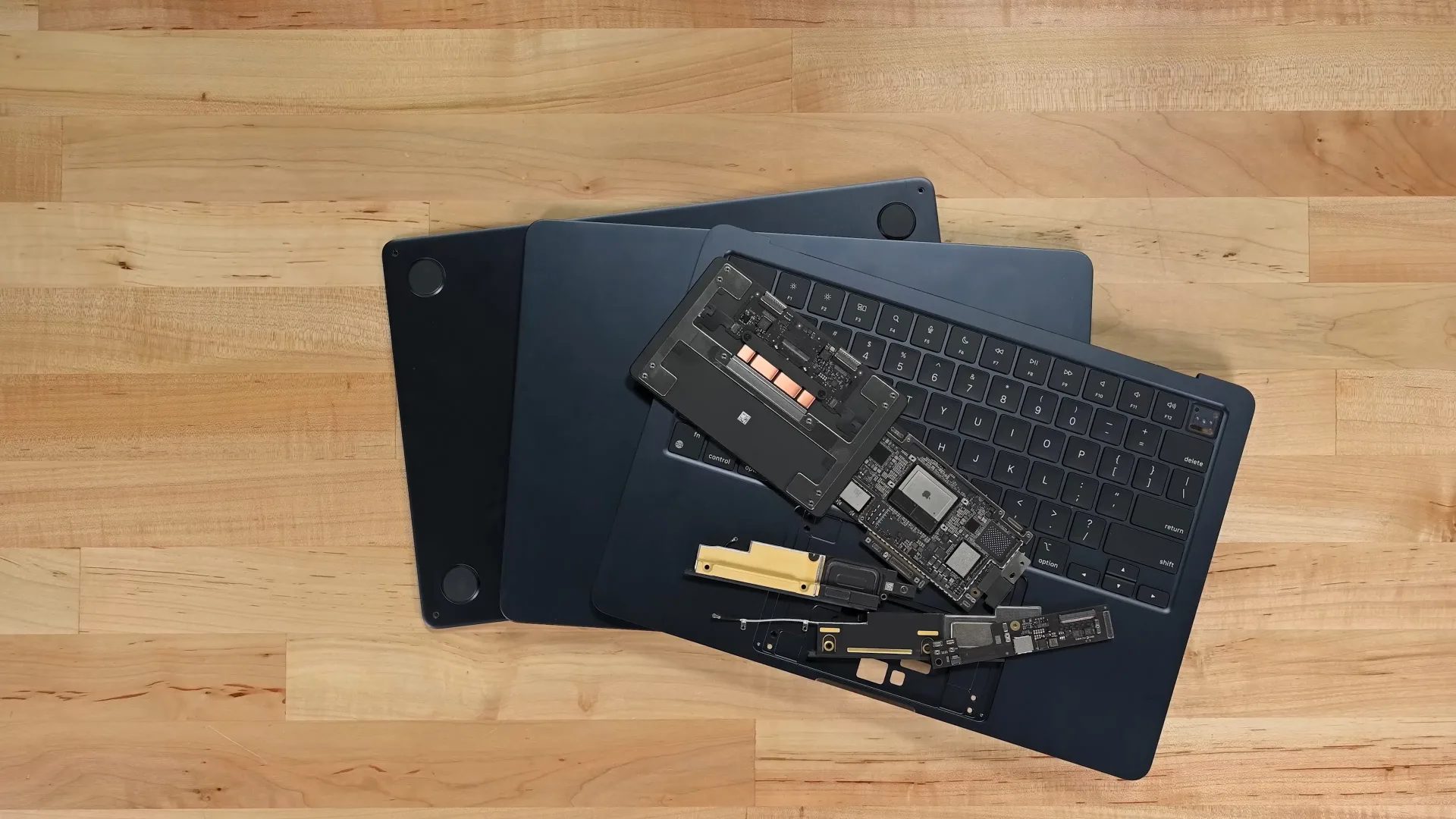 Le MacBook Air M2 démonté repose sur un plancher en bois.
