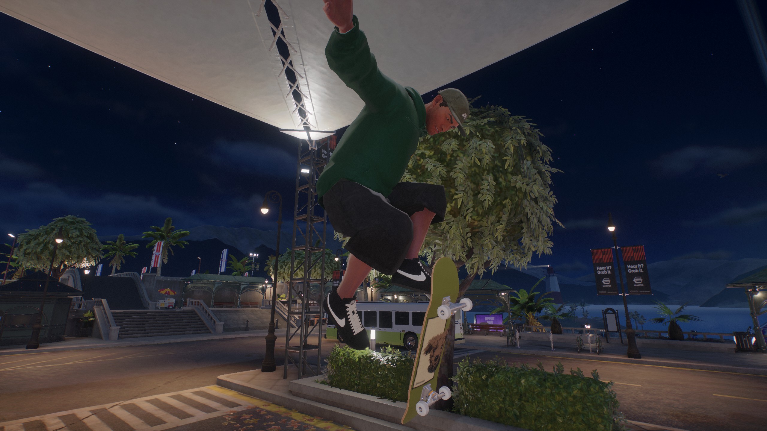 A skateboarder in 'Session: Skate Sim' performs an ollie near a city street at night, surrounded by palm trees and lit by streetlights.