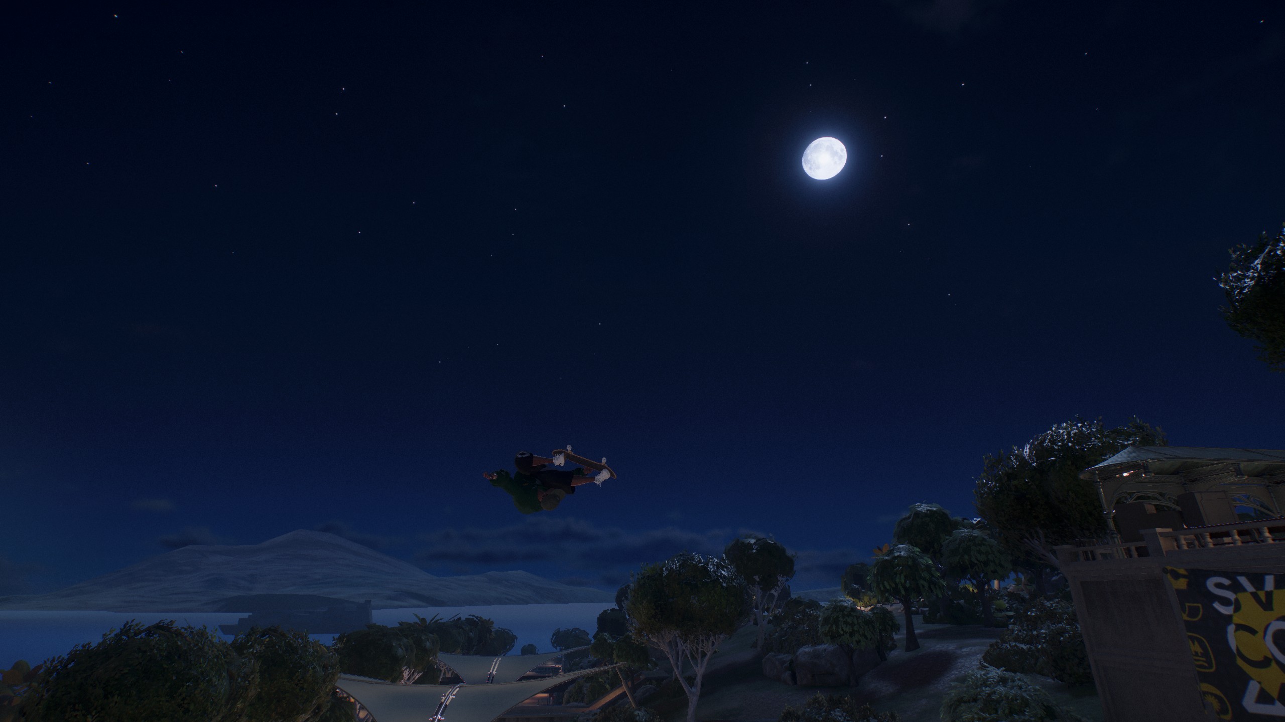 A skateboarder performing a trick in mid-air under the moonlit sky in a video game setting featuring a coastal landscape with trees.