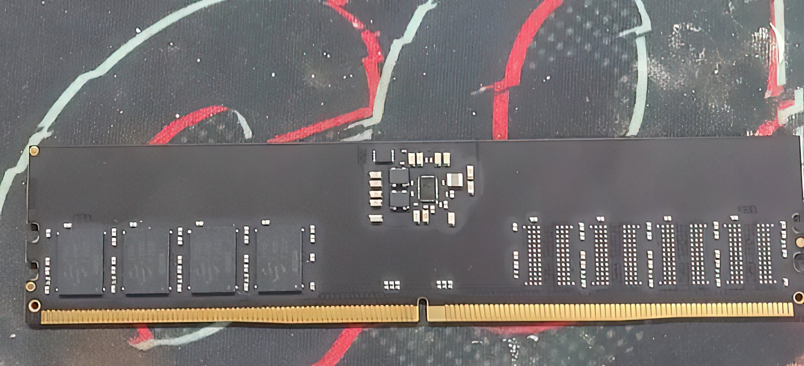 A close-up of an unbranded RAM module on a patterned surface, showing chips and connectors.