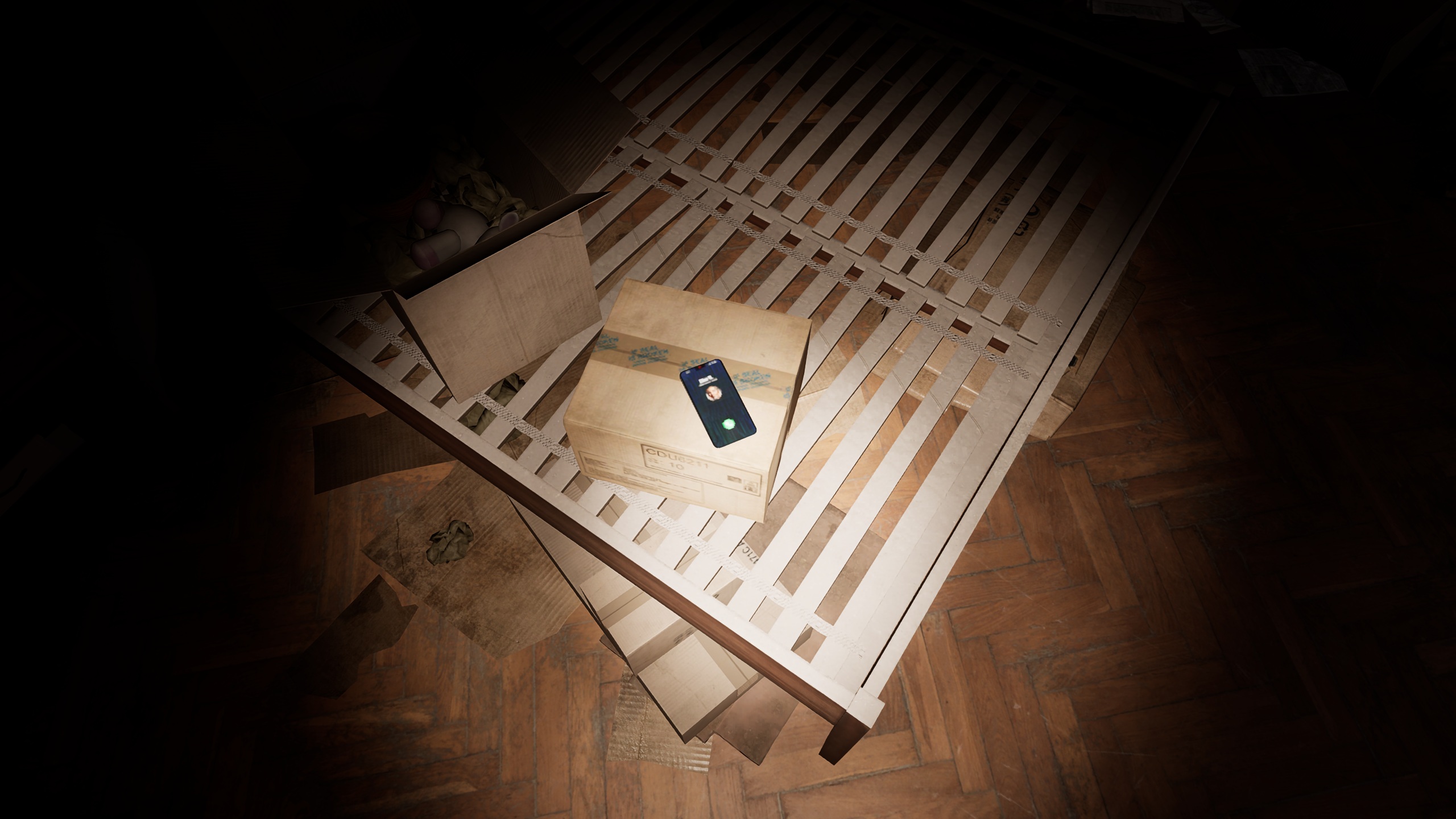 A smartphone displaying an incoming call interface is placed on top of a cardboard box on a wooden bed frame in a dimly lit room.
