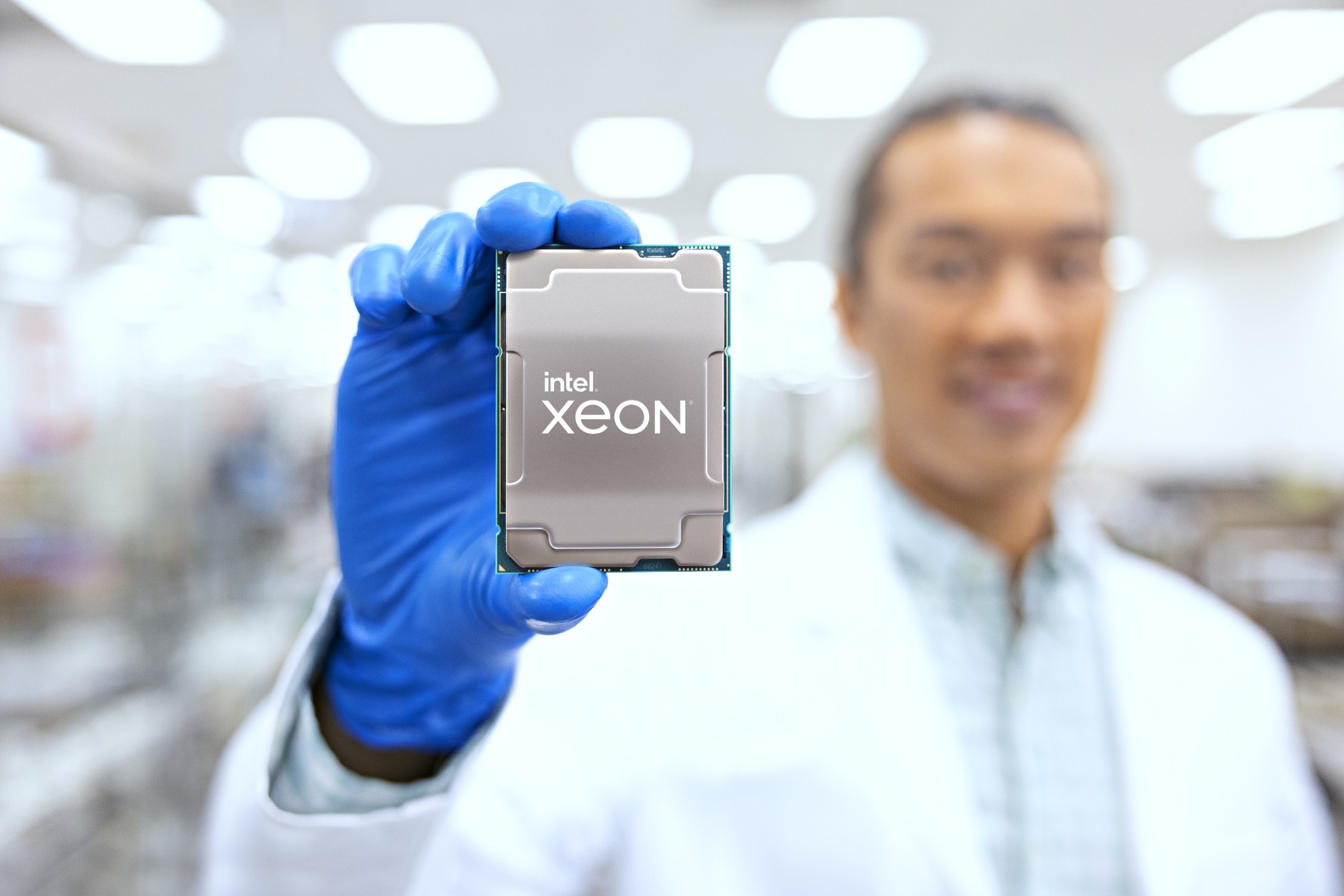 Une personne en blouse tient un processeur Intel Xeon dans un laboratoire.