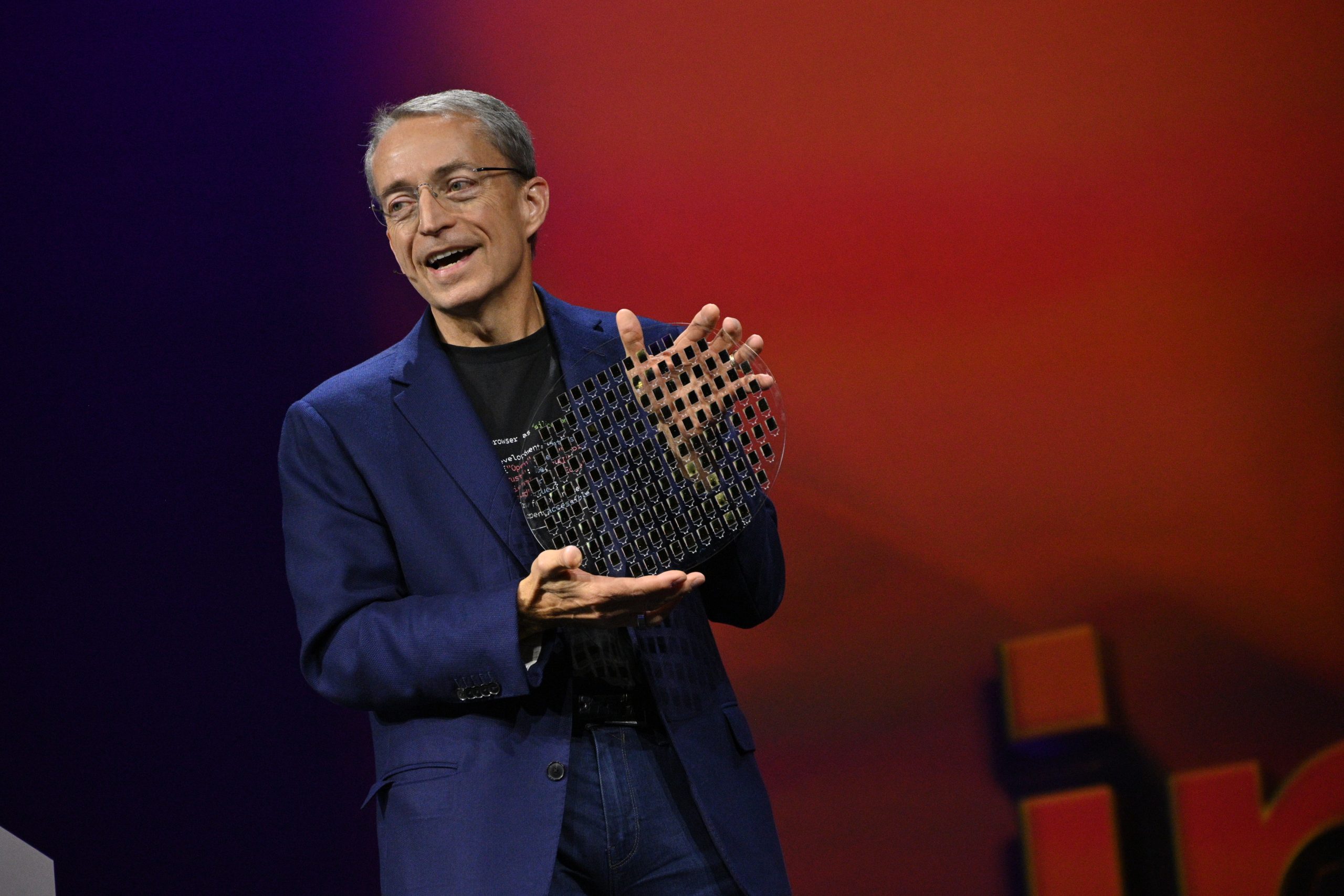 Intel CEO Pat Gelsinger tient un wafer porteur en verre avec des piles de puces photoniques en silicium.
