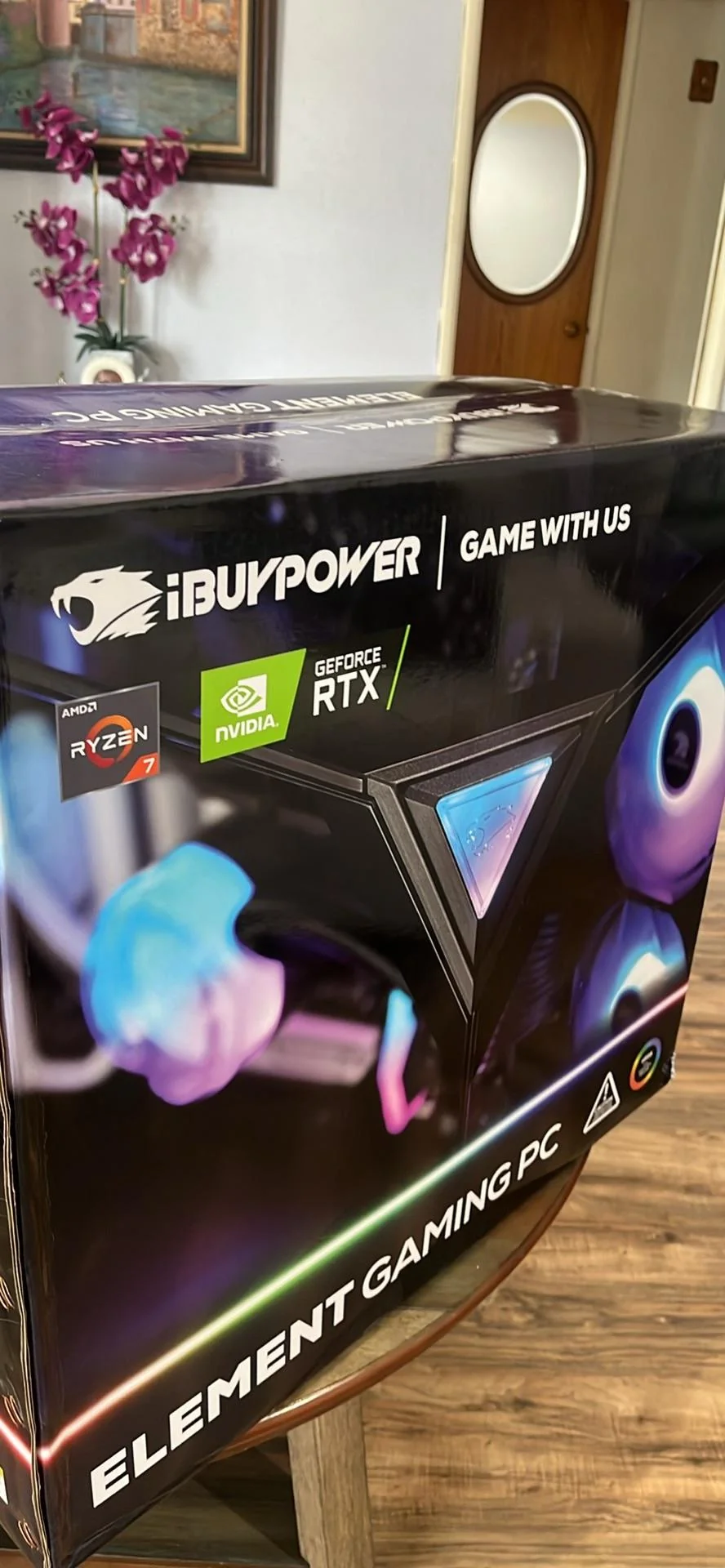 A box displaying the iBUYPOWER Element Gaming PC featuring AMD Ryzen 7 and NVIDIA GeForce RTX logos, with the text 'Game with us'.