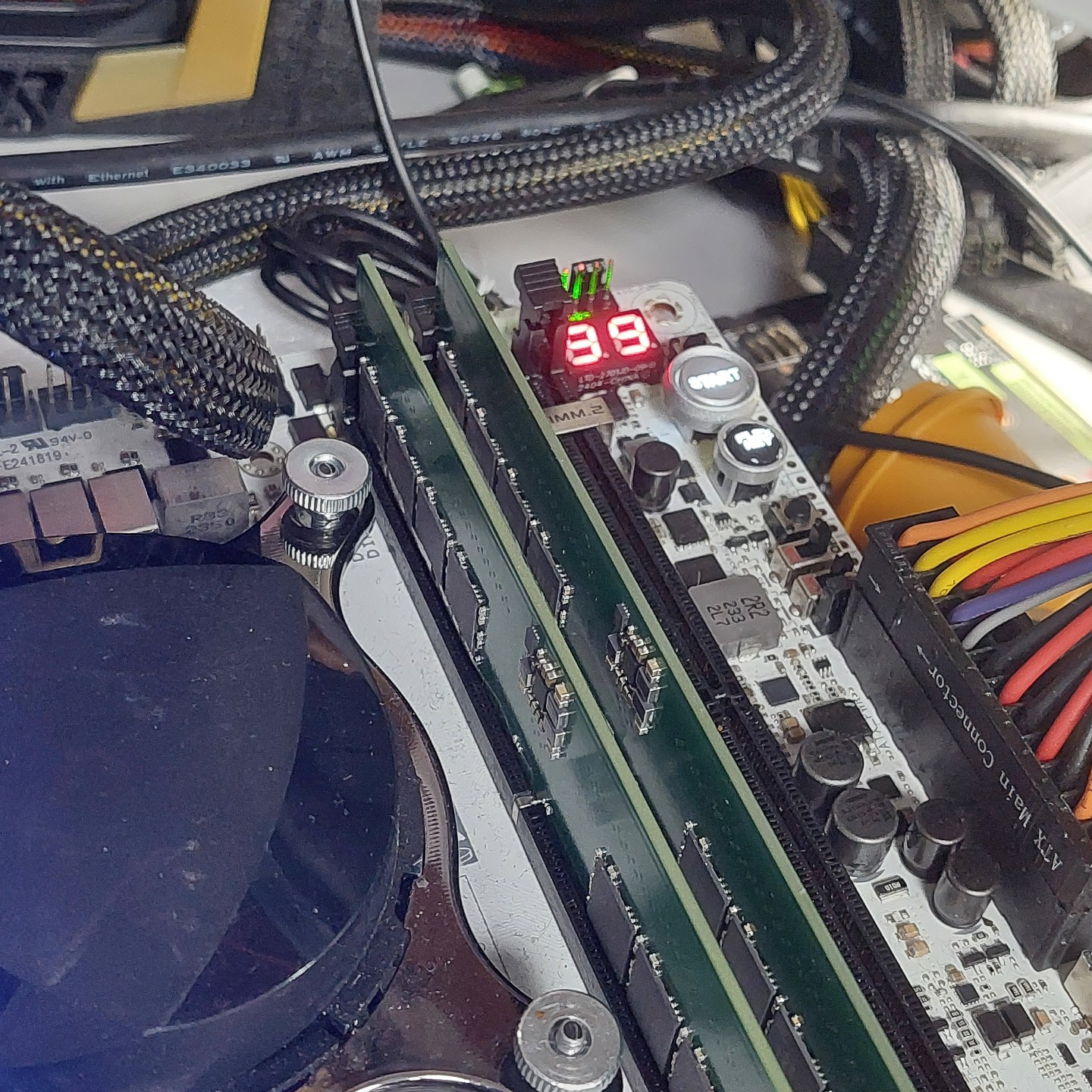 A computer motherboard with dual RAM sticks installed and a digital display showing '39' next to power connectors and cables.