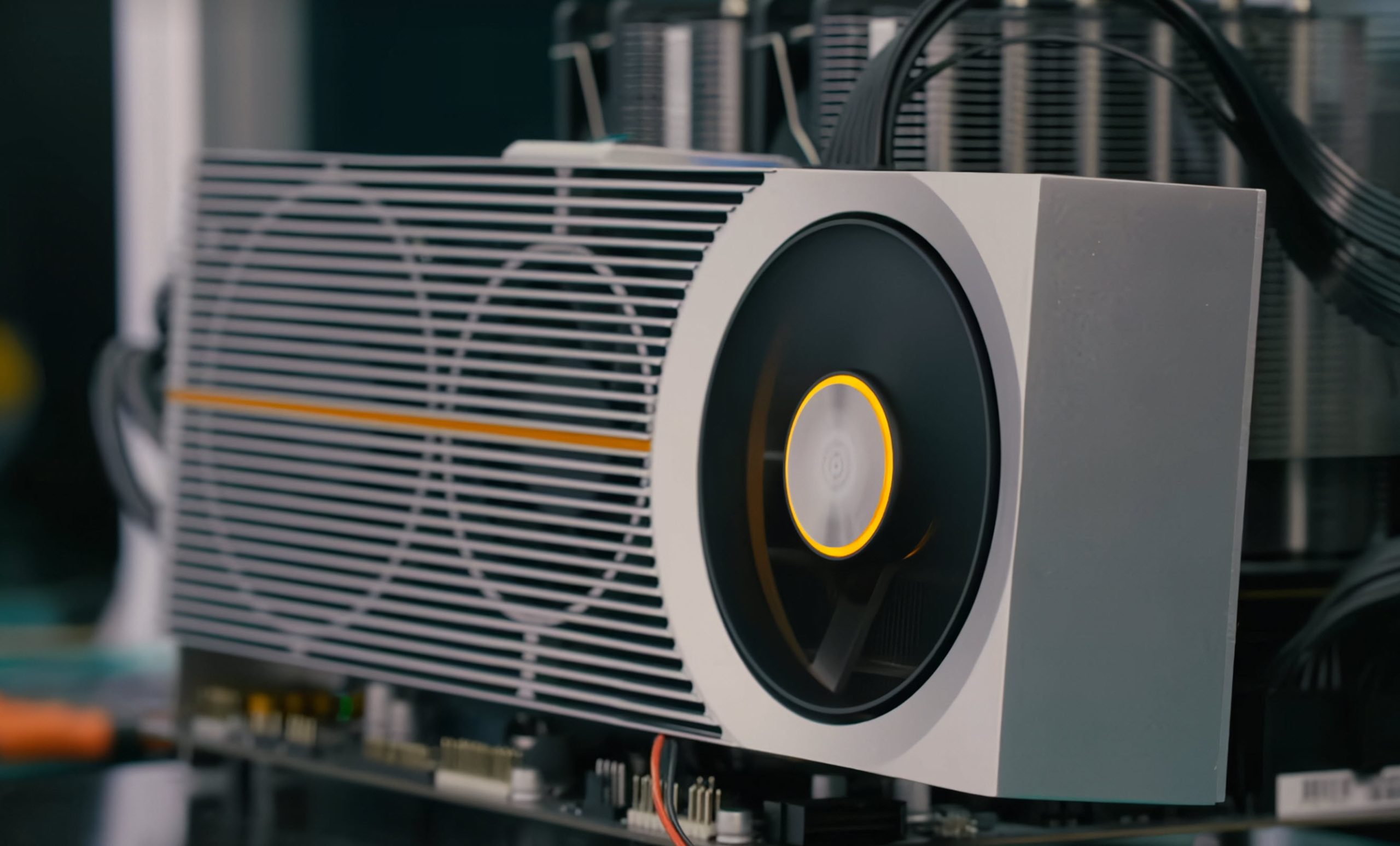 A close-up of the AMD Radeon RX 7900 GRE graphics card with a unique white and silver fan design and an orange stripe accent.