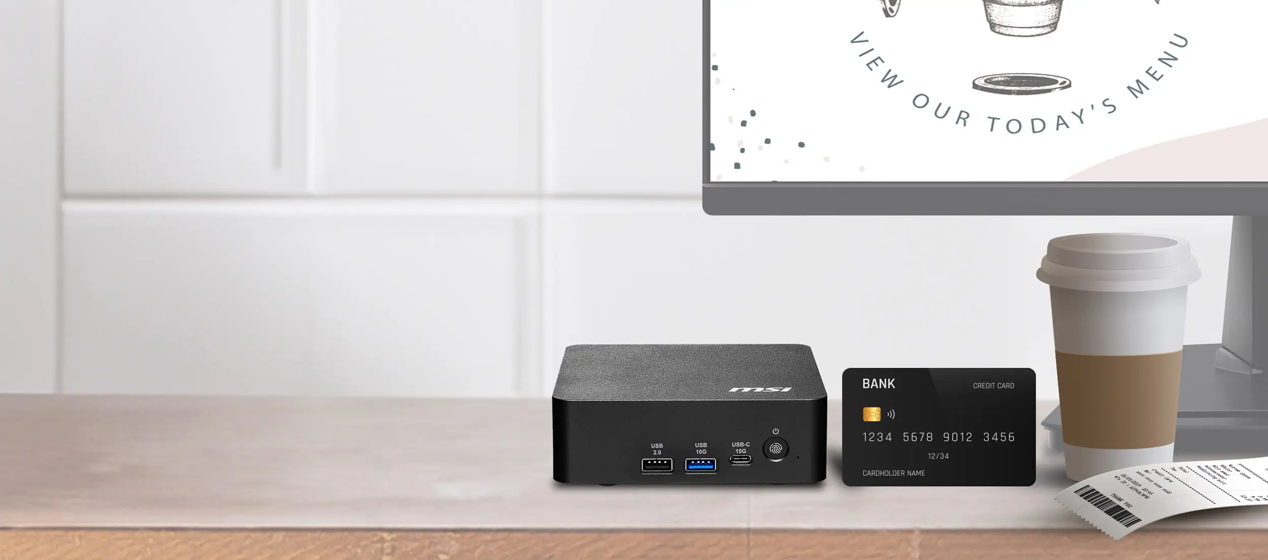 An MSI mini PC is placed on a counter next to a coffee cup, a credit card, and a receipt, with a monitor displaying 'VIEW OUR TODAY'S MENU' in the background.