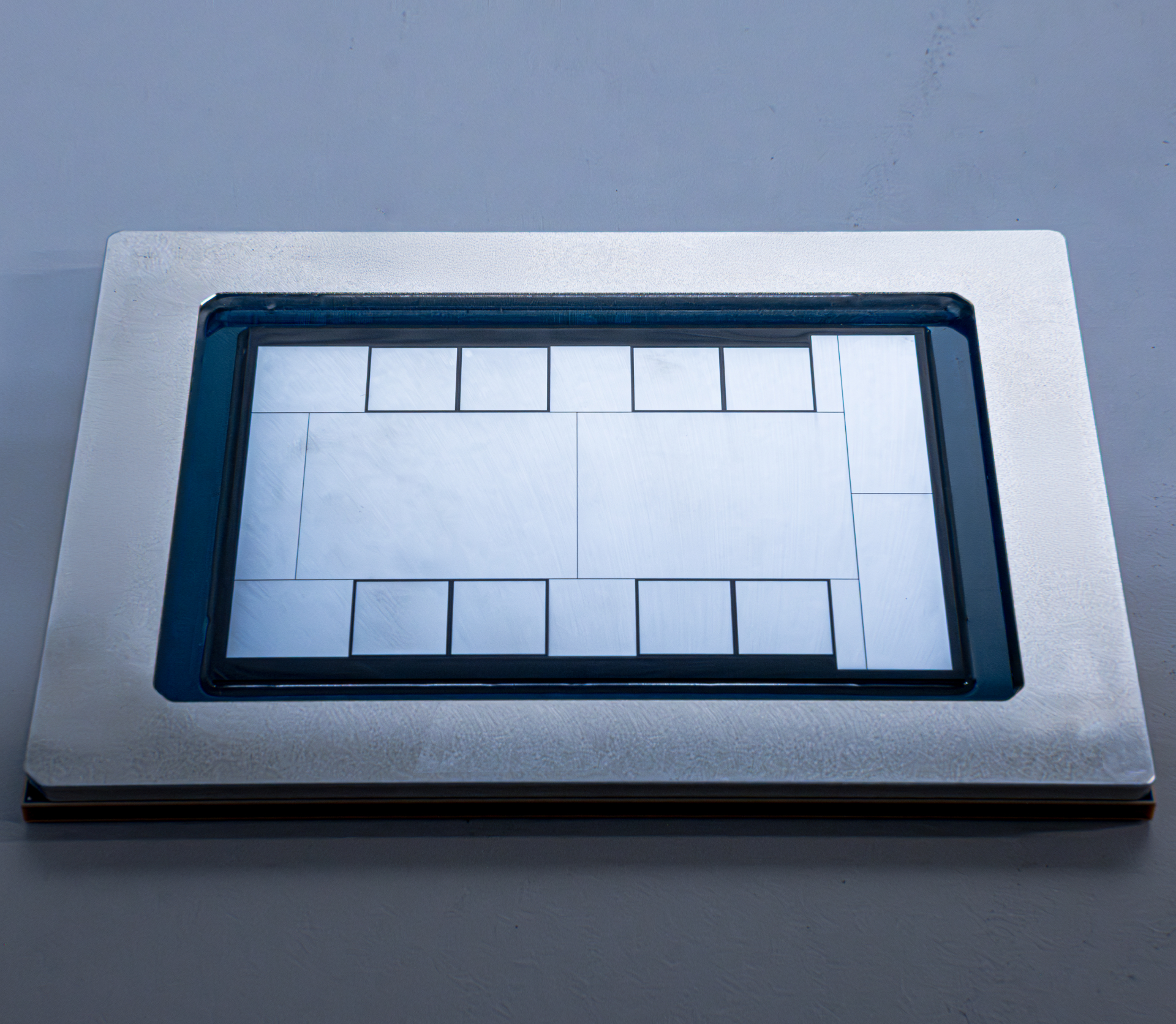 A close-up of a large silicon chip with visible rectangular patterns, possibly indicating its core layout and design.