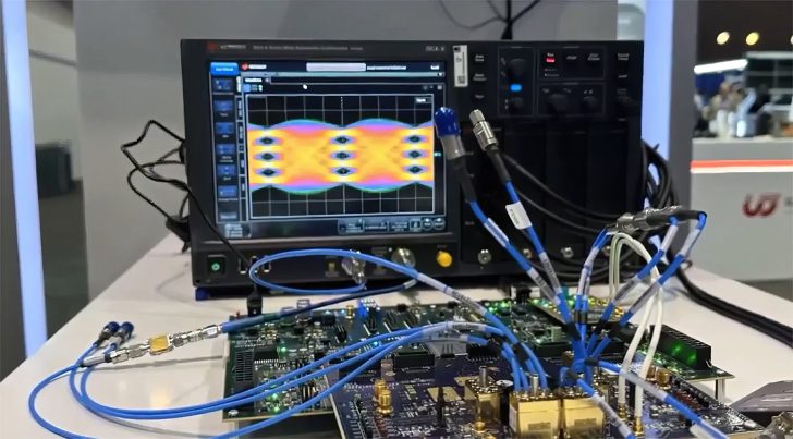 A Keysight Technologies Infiniium oscilloscope is displaying a multi-colored waveform pattern while connected to various electronic components on a circuit board with numerous blue cables.