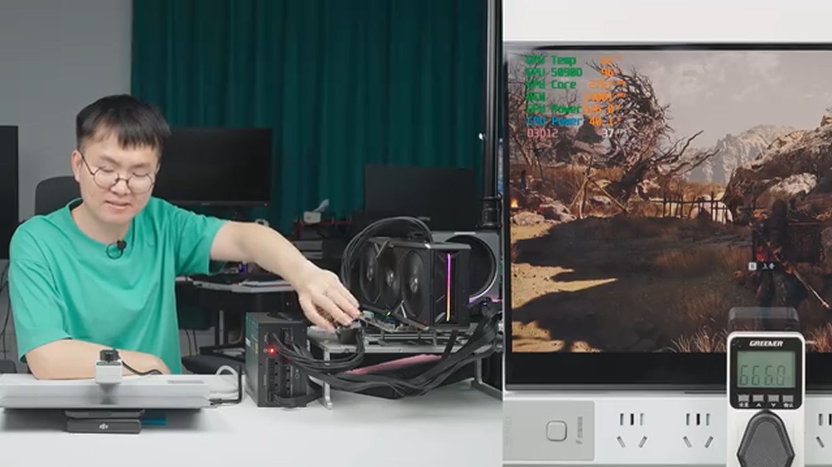 A person wearing a green shirt is adjusting hardware on a test bench while a monitor displays gameplay with on-screen data showing CPU temperature, usage, and power statistics.