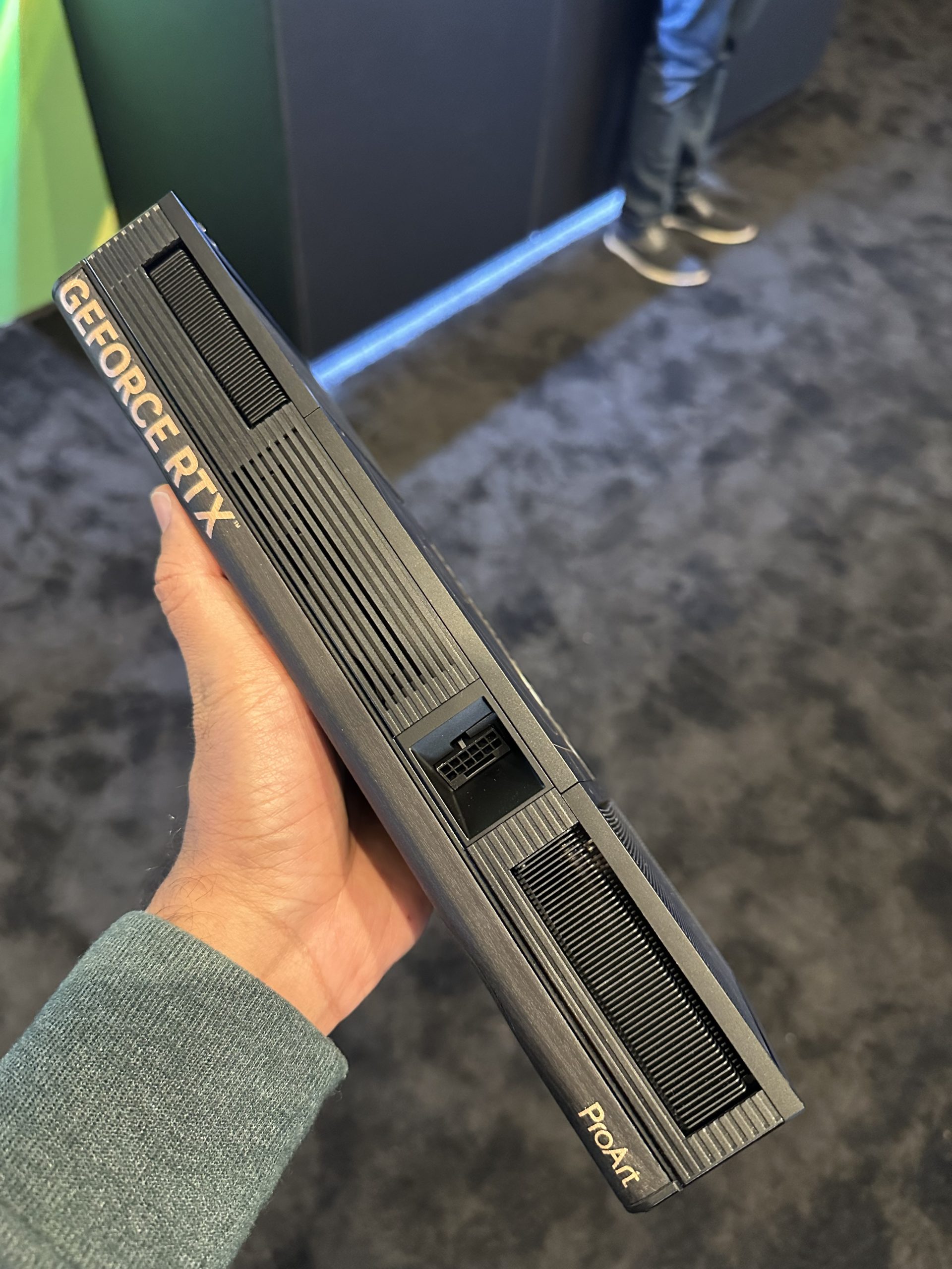 A person holding an ASUS ProArt GeForce RTX graphics card, showing the side with the 'GeForce RTX' and 'ProArt' markings.