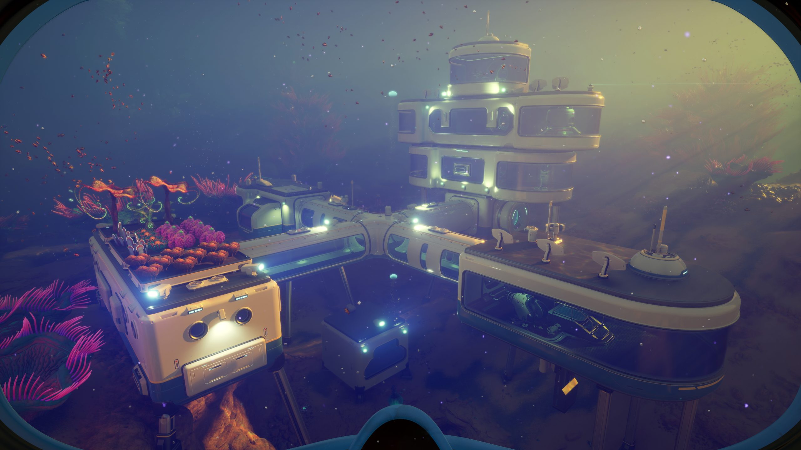 An underwater base illuminated with lights, featuring interconnected modules and vibrant coral in an ocean setting from the game Subnautica.