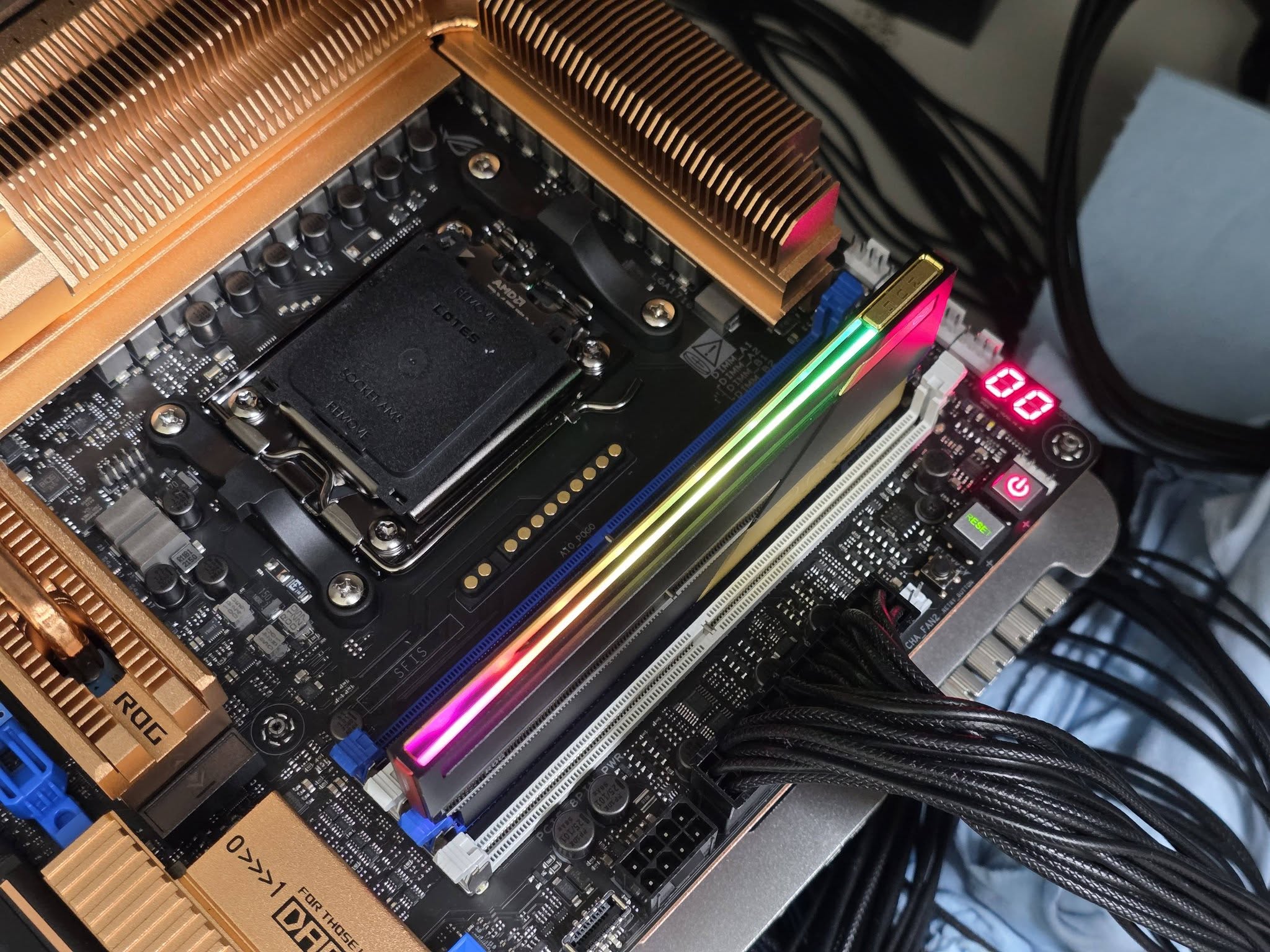 Une carte mère ASUS ROG avec socket Lotes, RAM RGB et radiateurs en cuivre.
