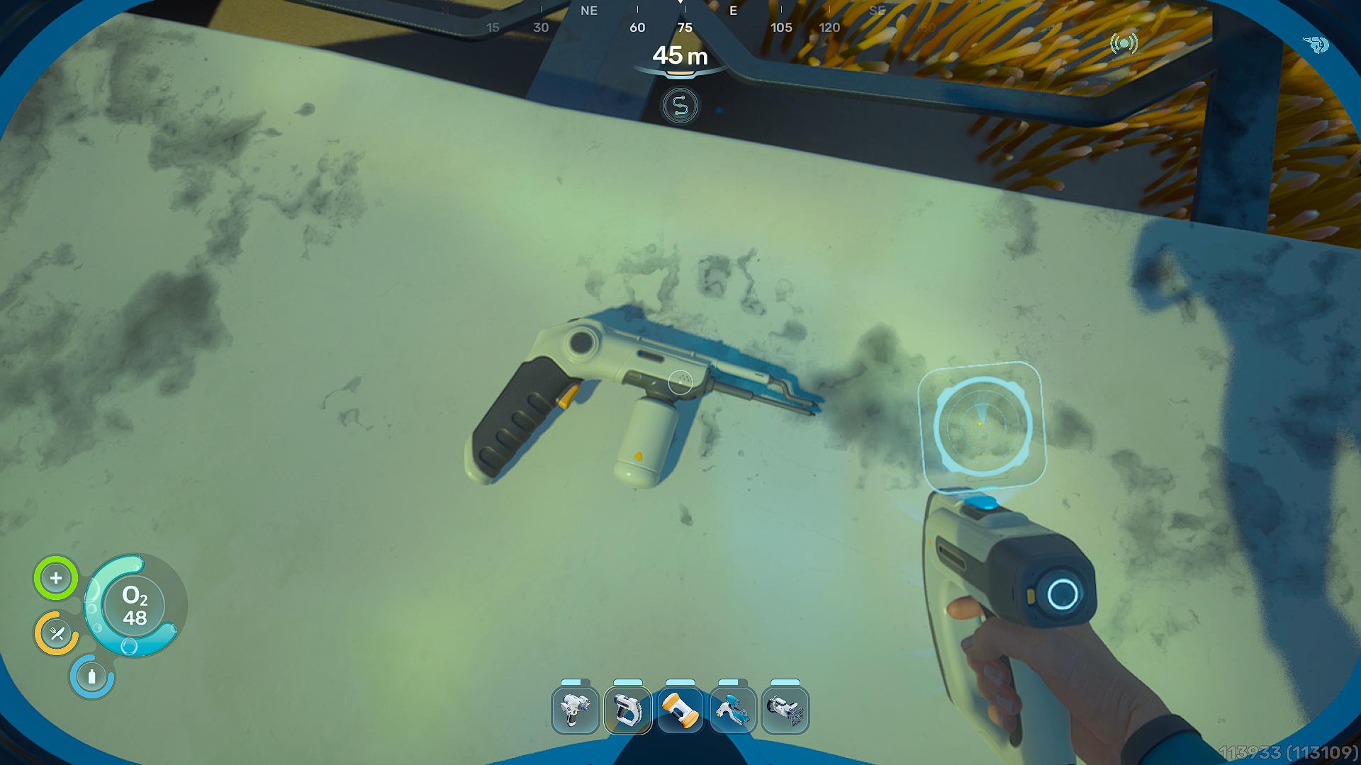 Un joueur dans 'Subnautica 2' utilise un outil de réparation sur une structure endommagée sous l'eau à une profondeur de '45 m', avec une interface affichant les niveaux d'oxygène et les options d'outil.