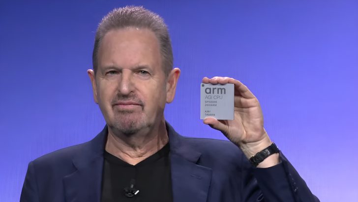 A person holding an ARM-powered AGI CPU with 'ARM' and 'AGI CPU' inscribed on it against a blue background.