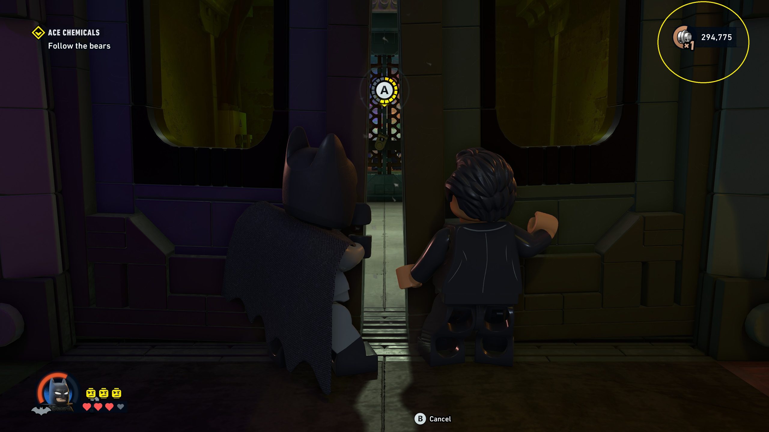 Dans 'LEGO Batman : Legacy of the Dark Knight', Batman et un autre personnage regardent par une porte entrouverte dans le niveau 'Ace Chemicals' avec l'objectif 'Suivre les ours'.