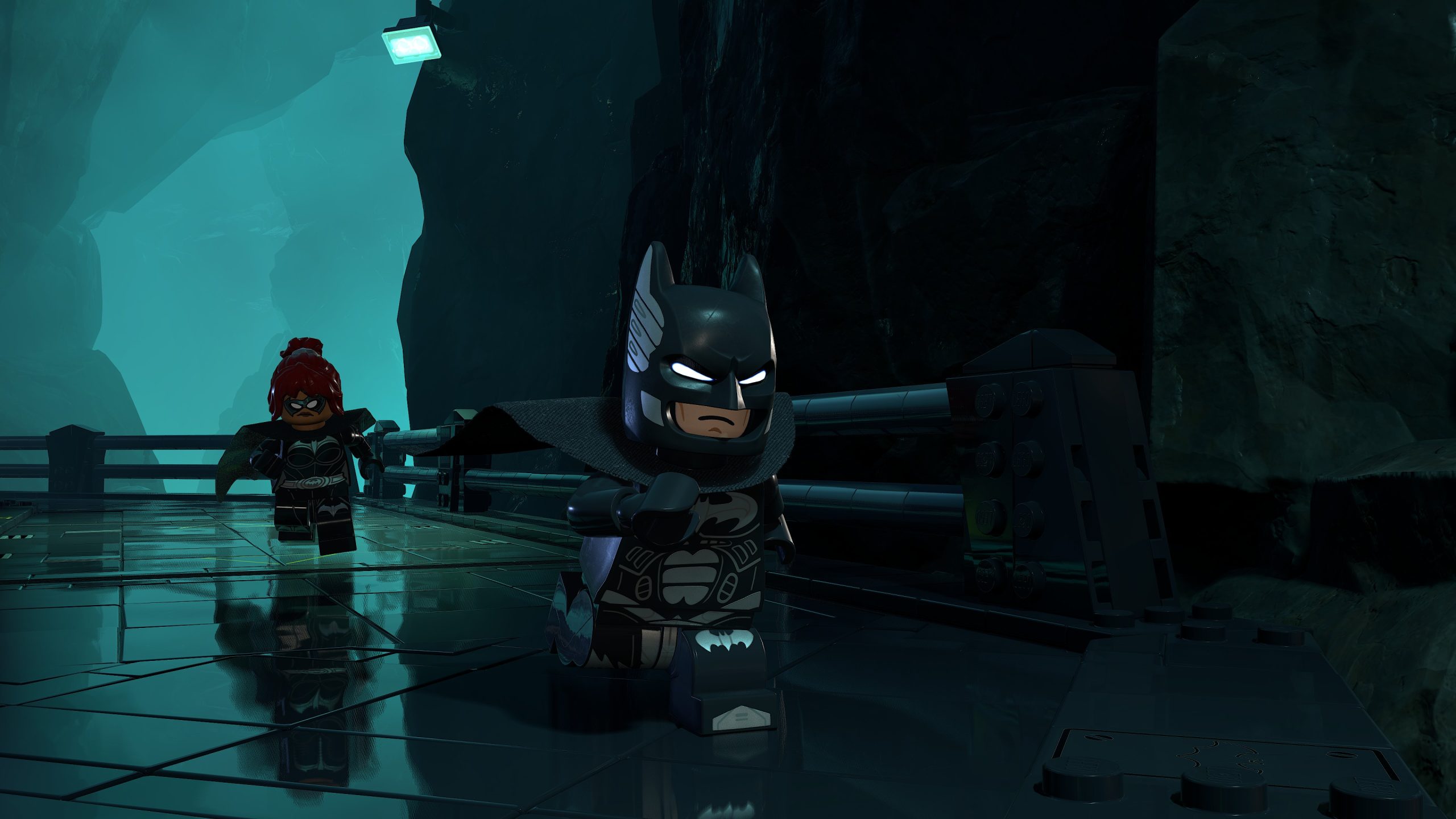 Une scène de LEGO Batman montre LEGO Batman et un autre personnage courant dans un environnement de type caverne.