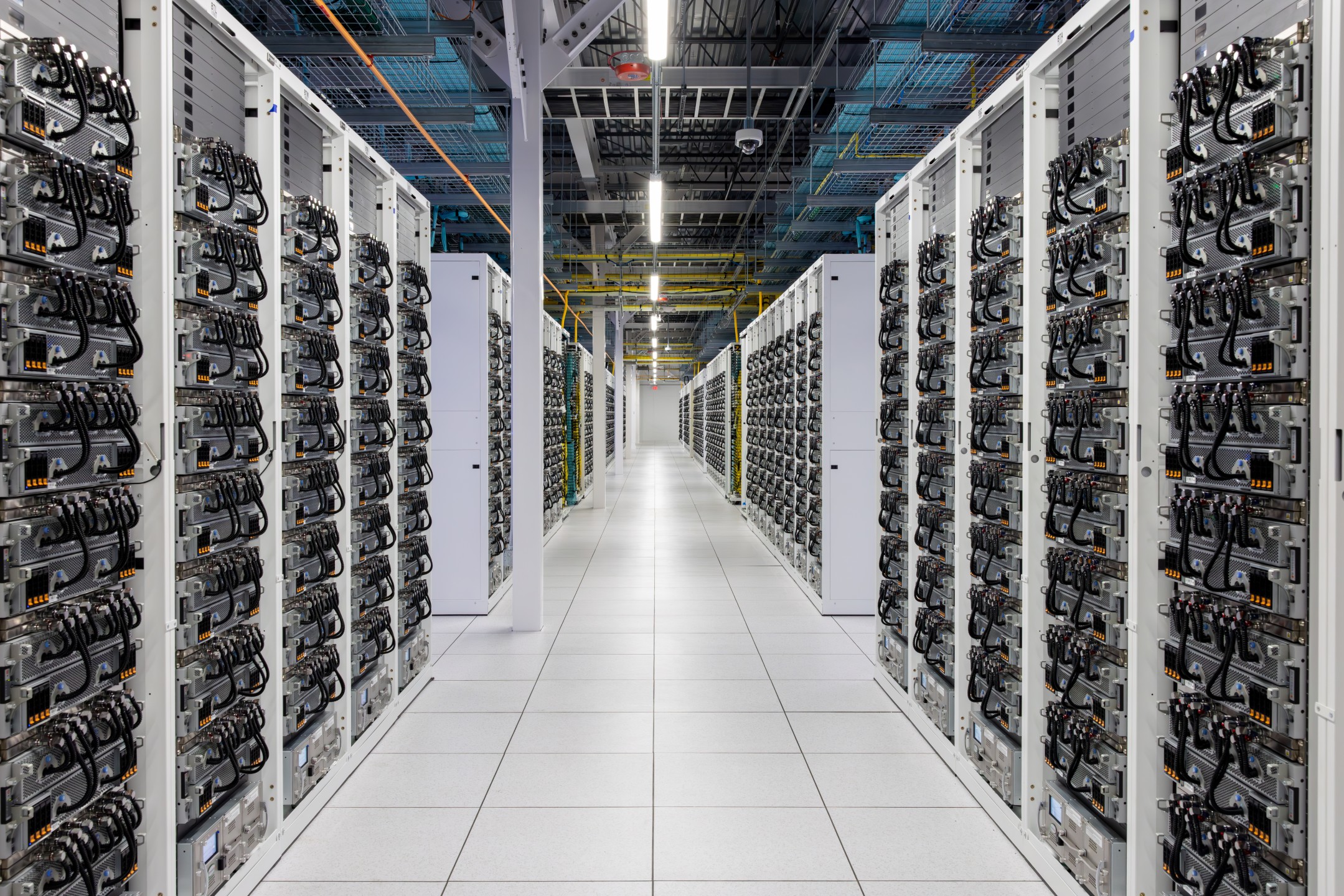 A large data center with multiple rows of server racks and visible cables neatly organized.