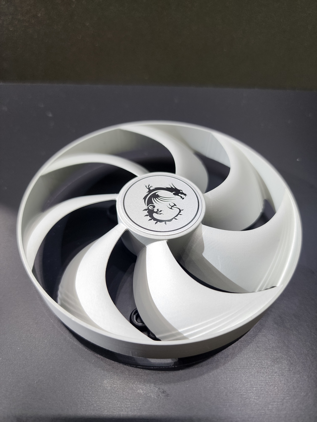 Un ventilateur de refroidissement avec le logo du dragon MSI en son centre, présenté sur un fond sombre.