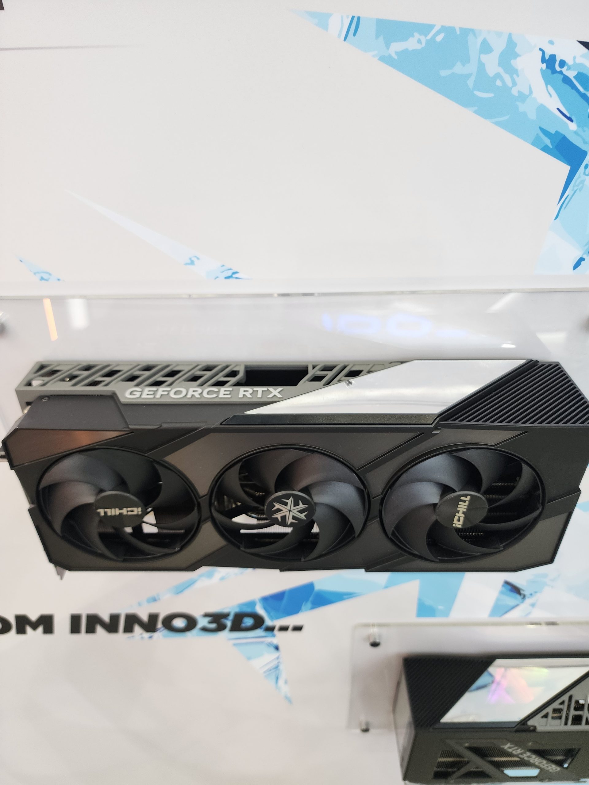 Une carte Inno3D RTX avec trois ventilateurs, sur un support.